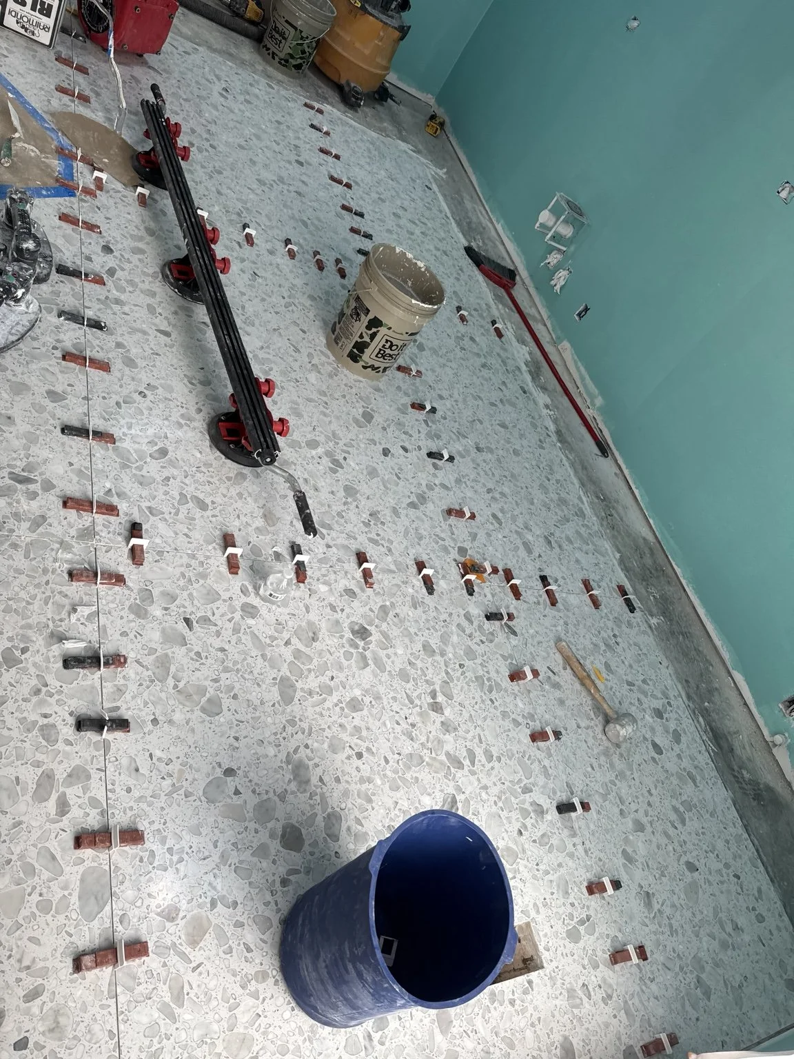 Precision large-format tile floor installation using leveling clips and spacers.
