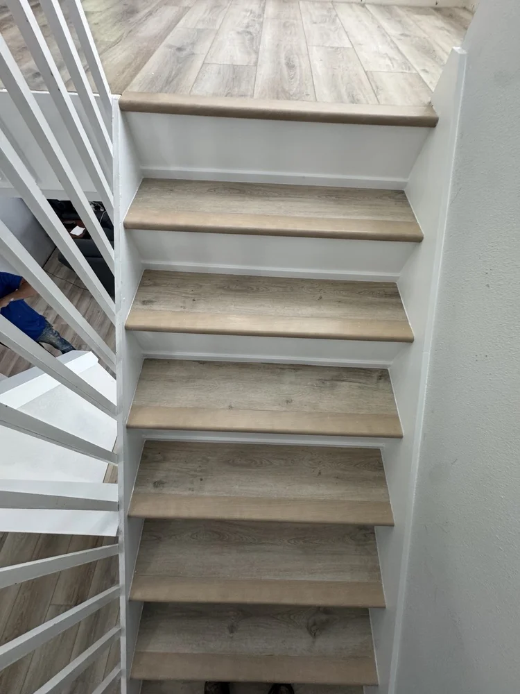 Light wood-look LVP flooring with matching stair treads and white risers.