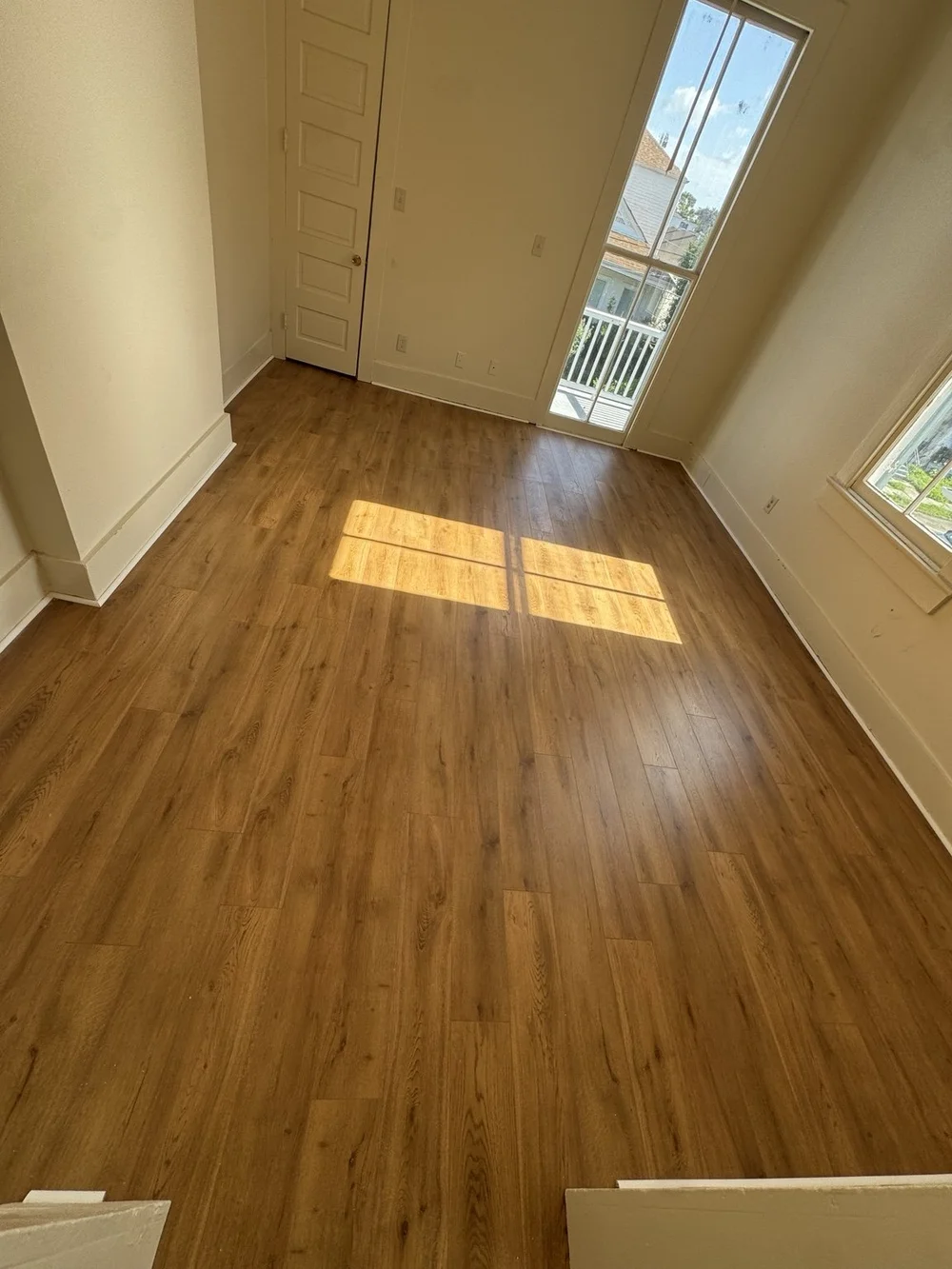 Warm wood-look flooring installed in a bright, sunlit room.