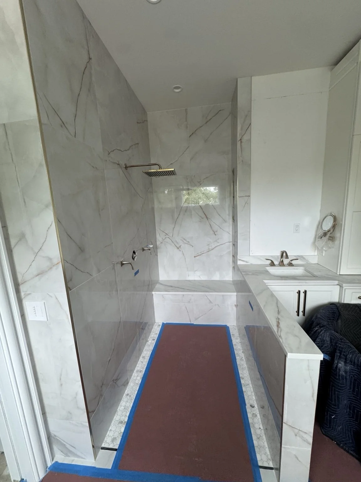 Custom bathroom featuring large-format porcelain tile, walk-in shower, bench, niche, and vanity.
