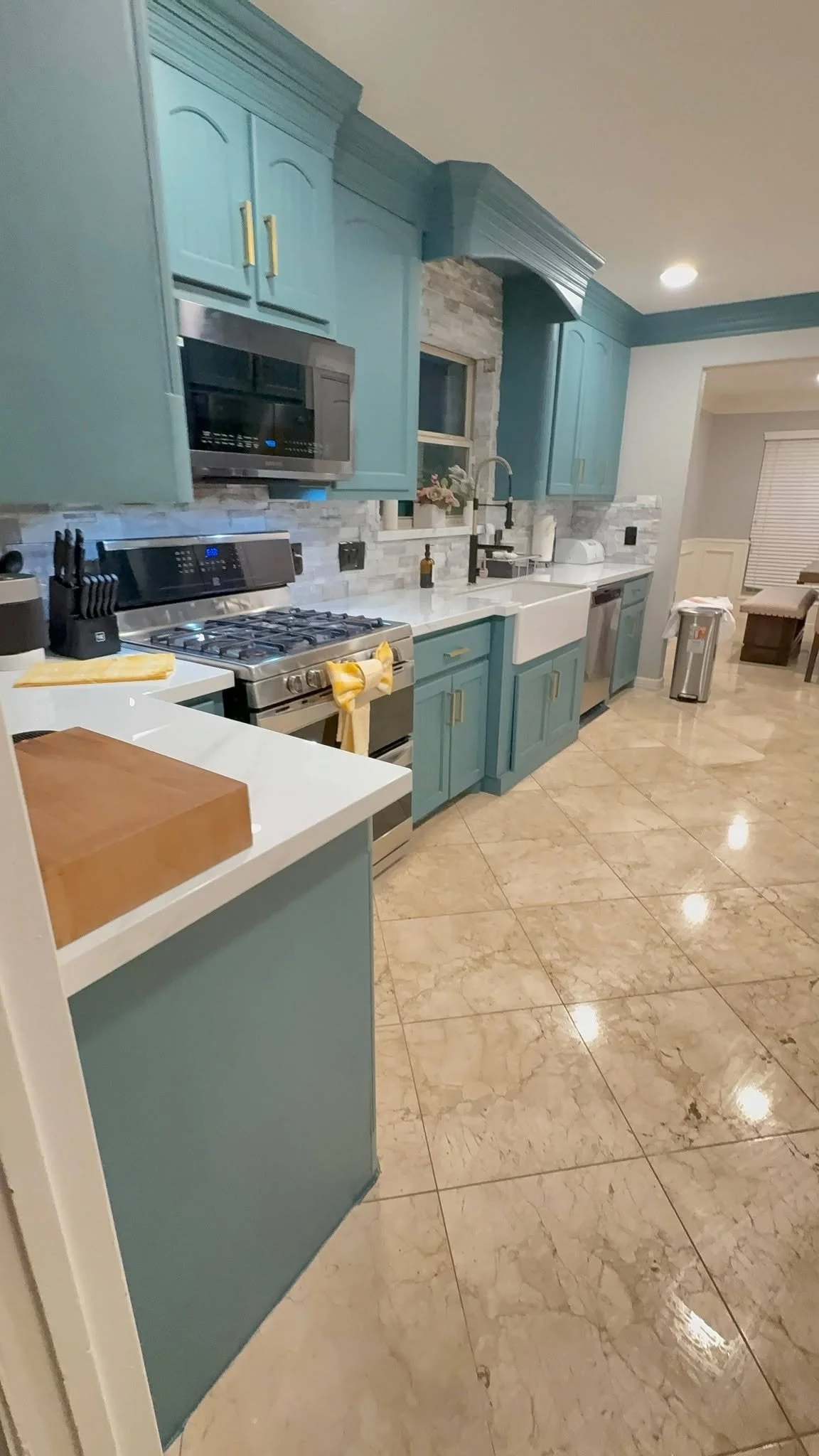 Clean kitchen with teal cabinets and marble tile floor after professional cleaning