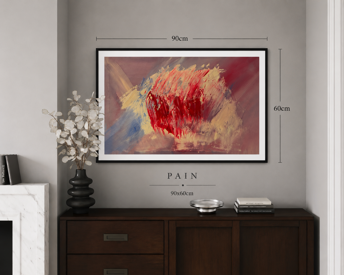 Abstract painting titled 'PAIN' hanging on a grey wall above a dark wooden sideboard, measuring 90cm by 60cm. The painting features bold brushstrokes in red, yellow, blue, and beige. To the left is a black vase with white eucalyptus branches. On the 