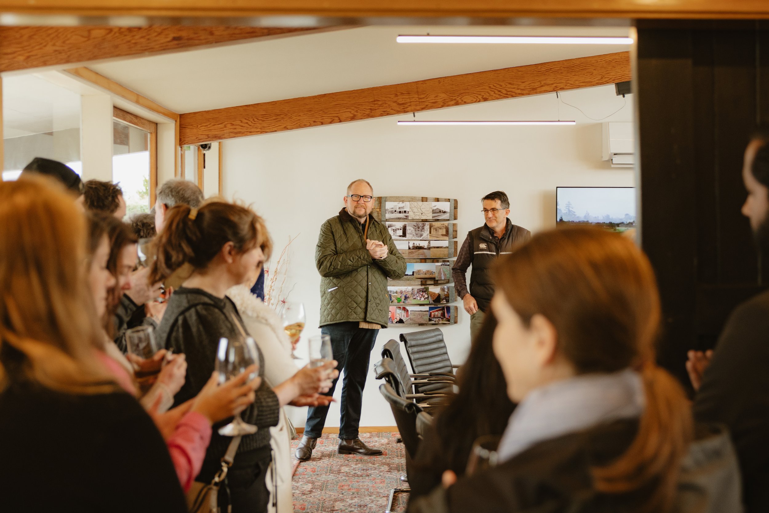 A group of people attending the opening event. The Mayor and owner standing at the front speaking to the audience.