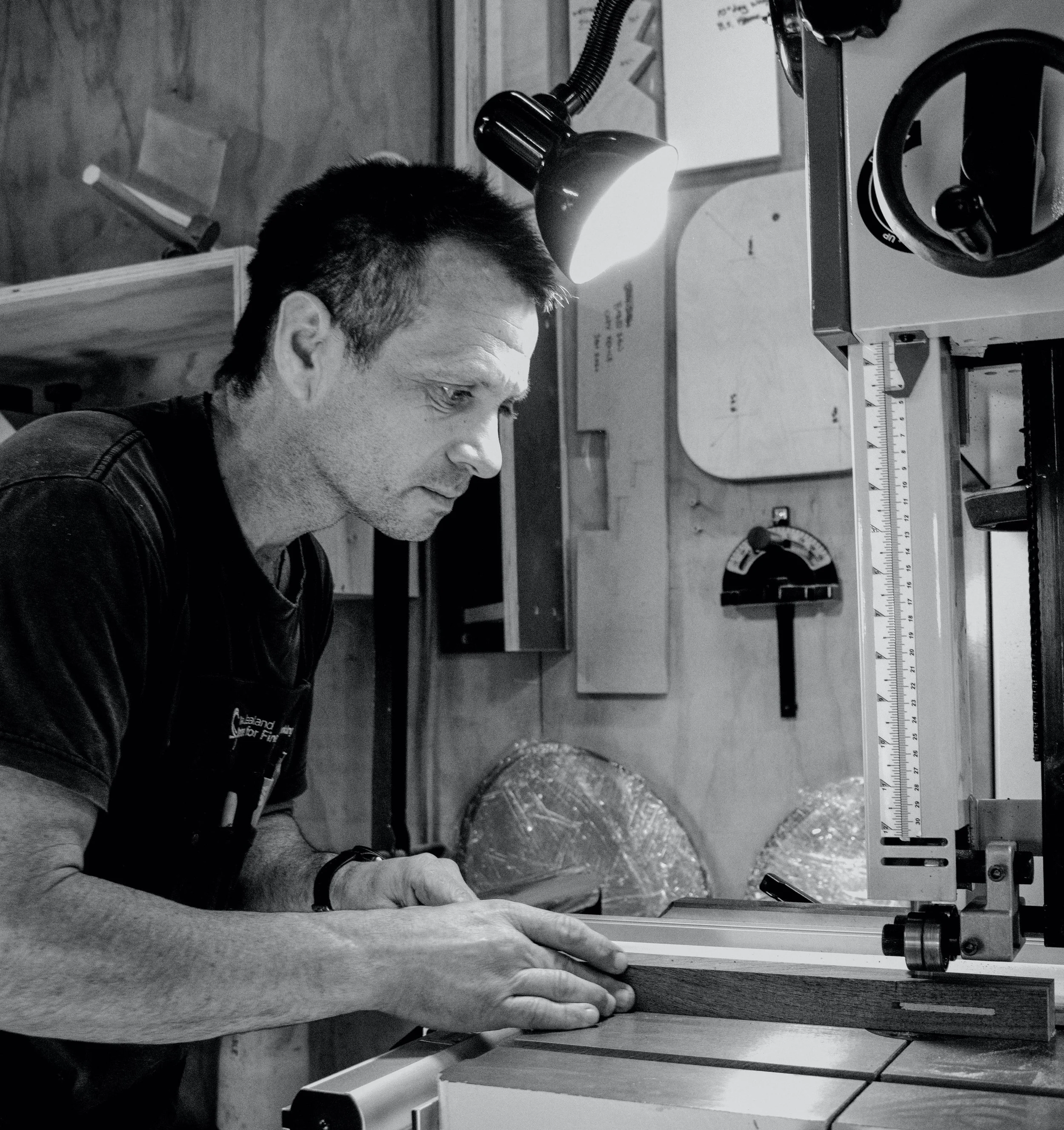 Ben Grant cutting timber on a table saw in his furniture workshop, Whaingaroa/Raglan, New Zealand
