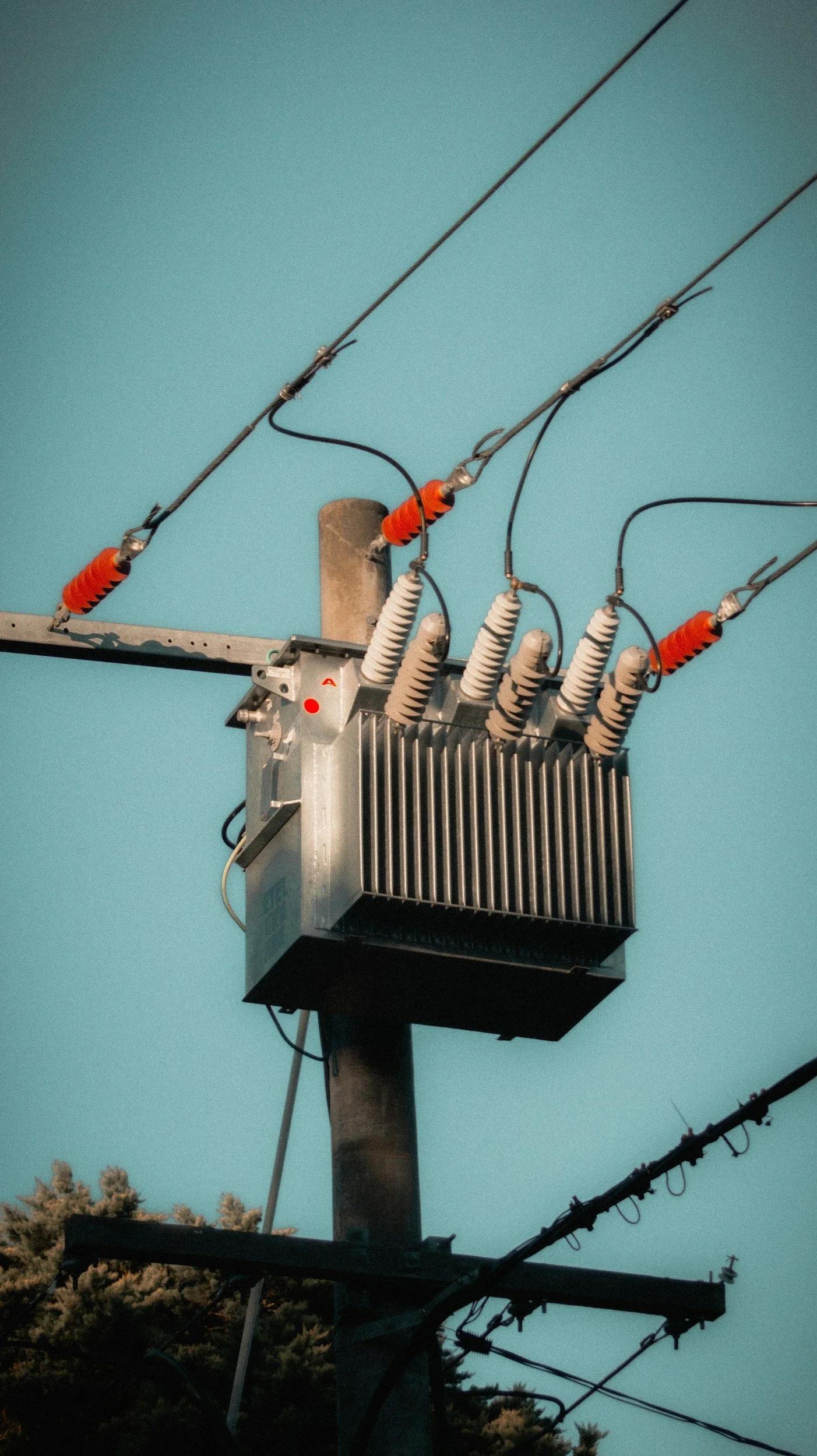 Close-up of an electric utility pole with insulators and electrical equipment against a sky background.