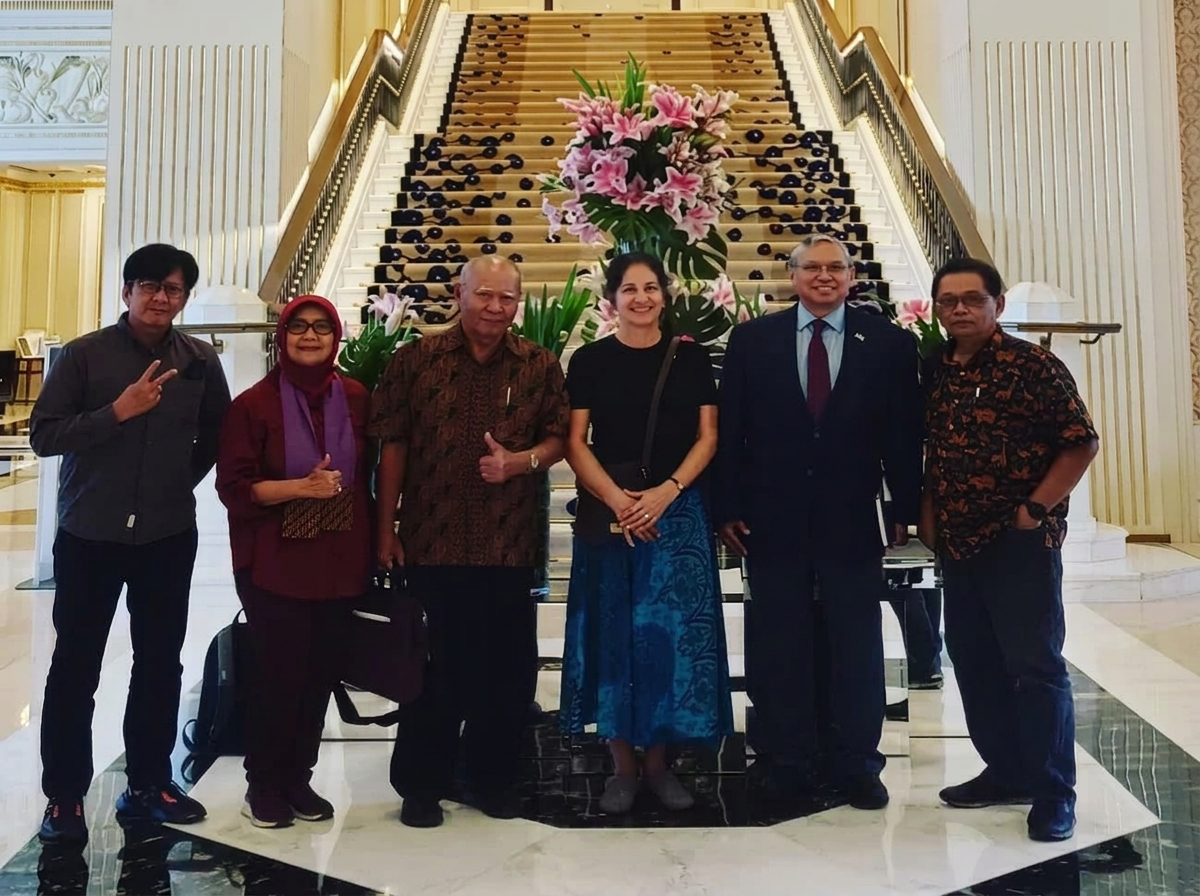 Group of six people standing in front of a floral arrangement on a staircase in a luxurious building.