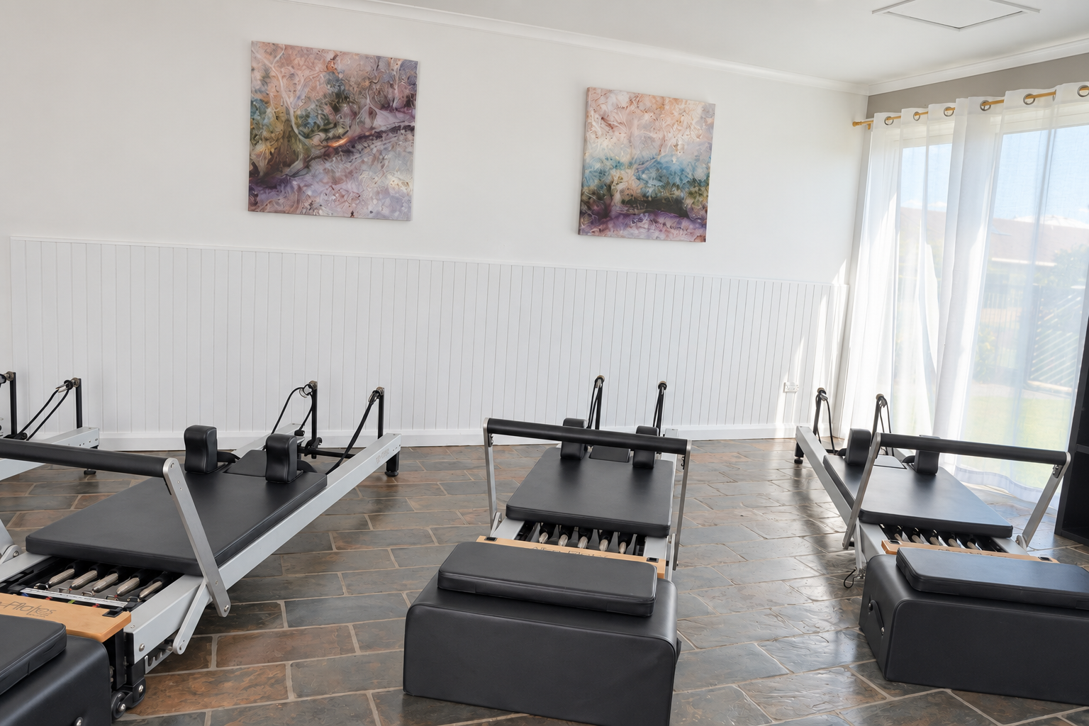 woman doing a stretch yoga pose on a reformer Pilates machine in a fitness studio.