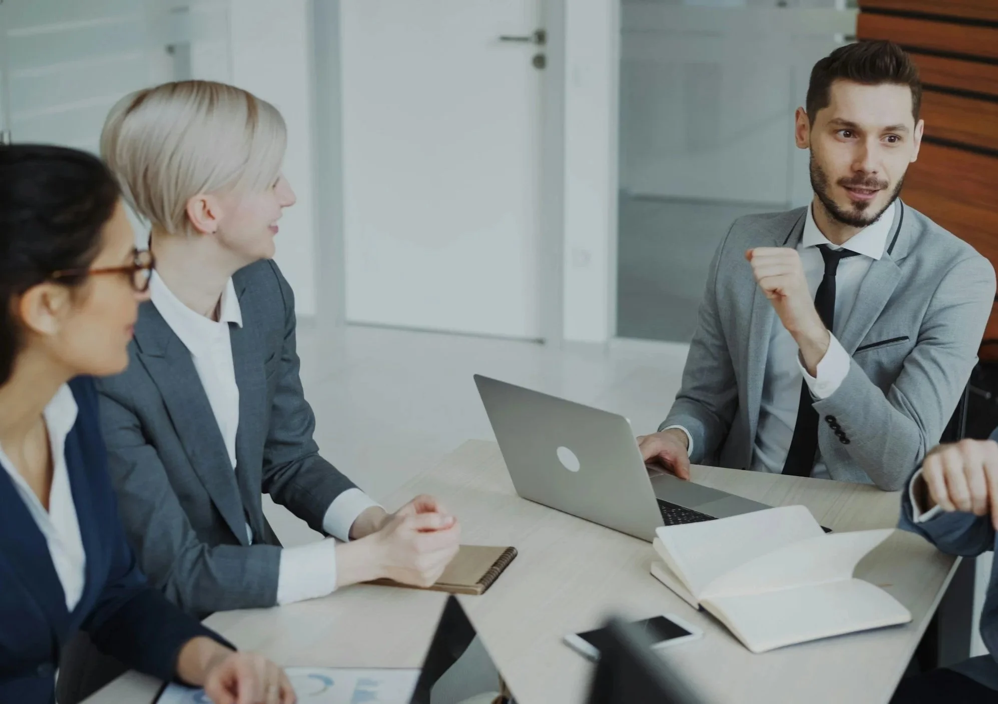Four colleagues discussing work around a conference table.