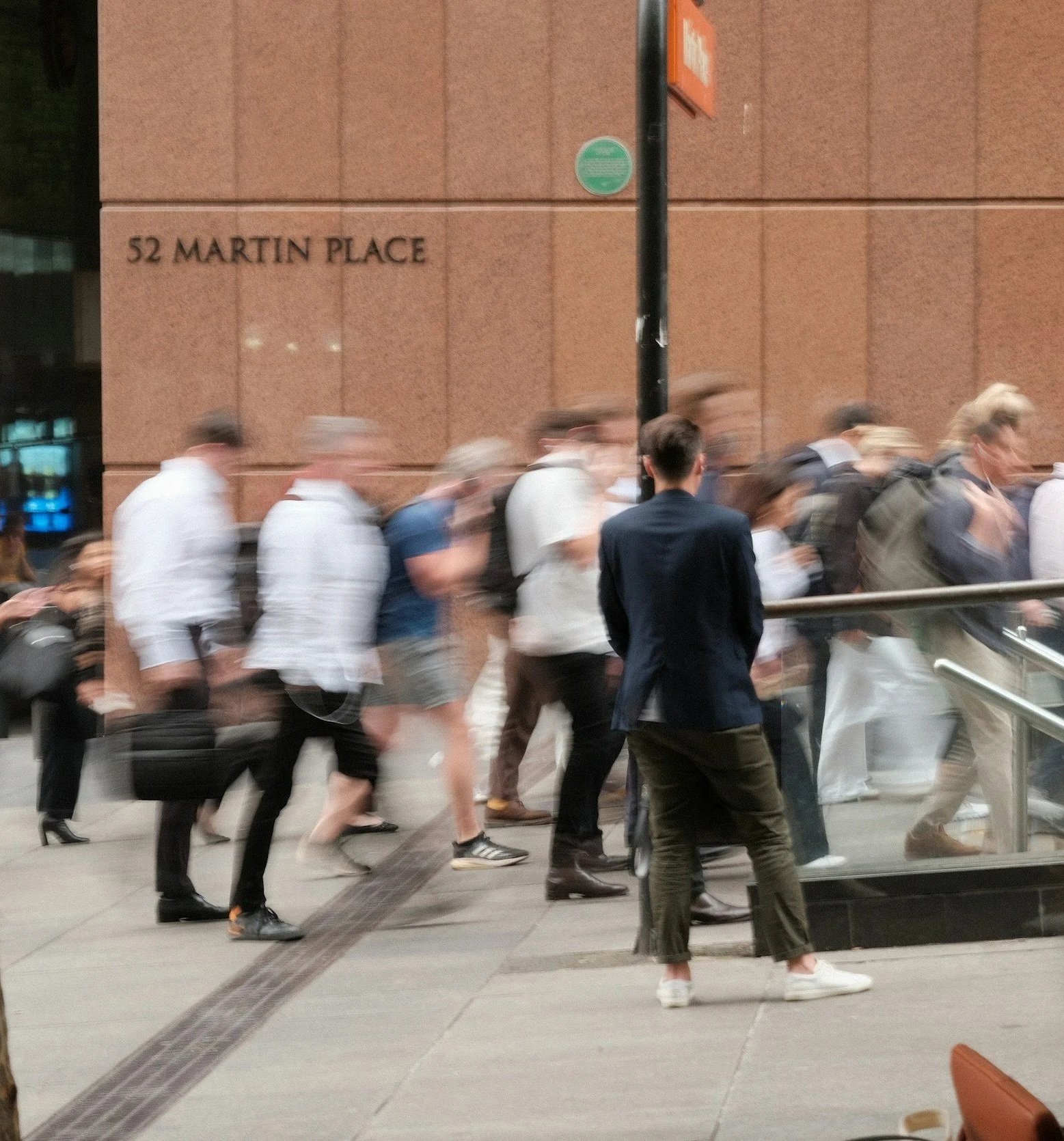 People walking along a city street beside a brick building.