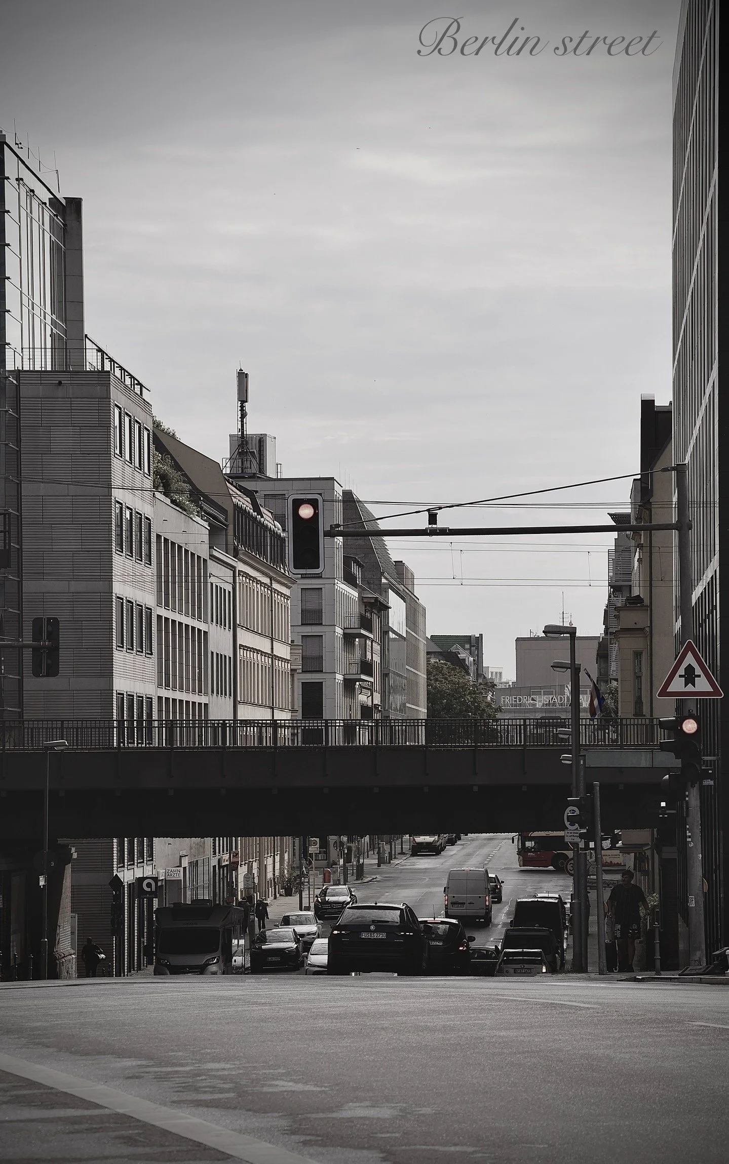 Black and white photo of a city street with modern buildings, traffic lights, cars, pedestrians, and an overpass, with the words 'Berlin street' at the top.