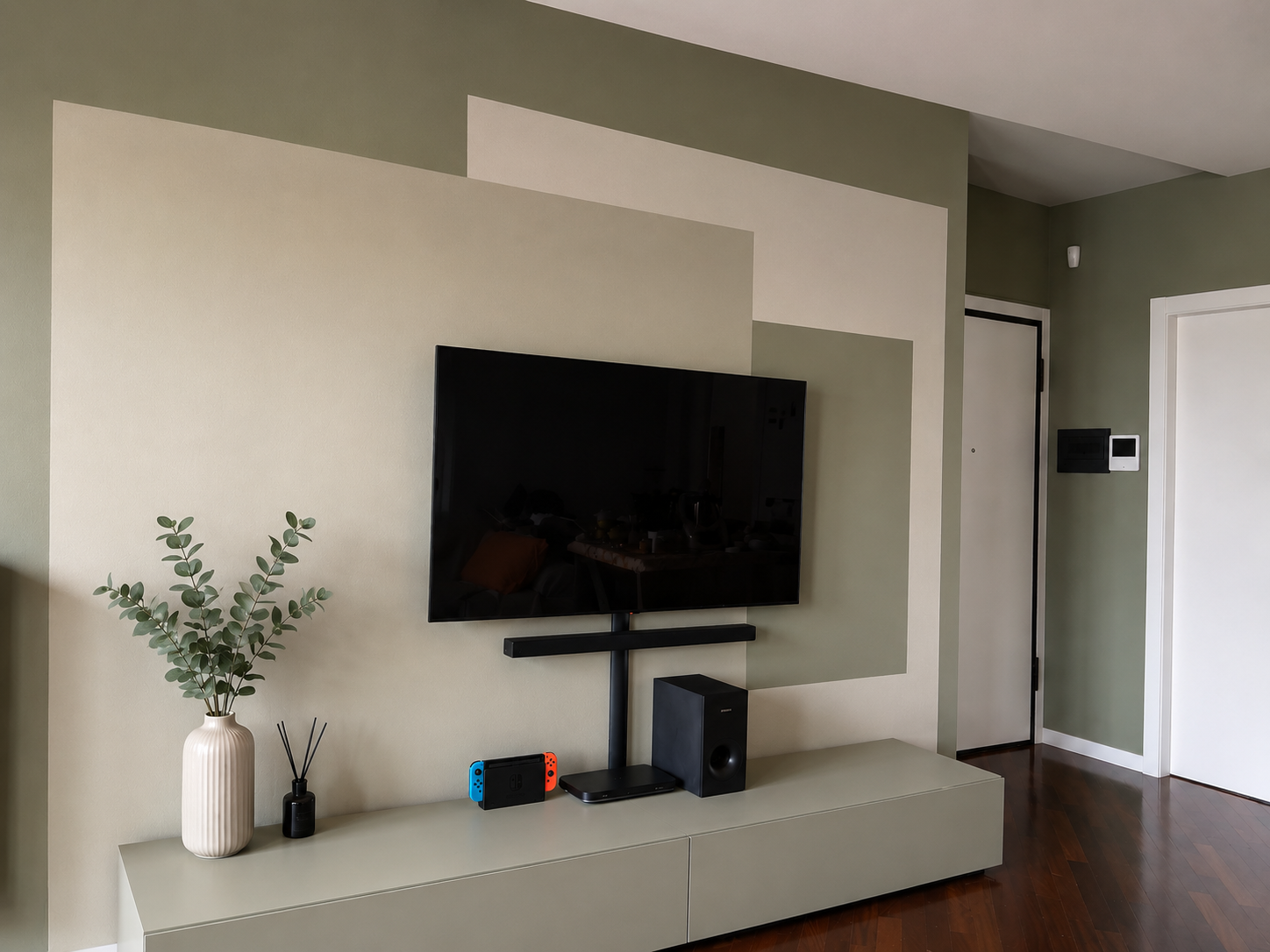Muro con decorazioni colorate, TV appesa, mobile con decorazioni, piante, speaker e console di videogiochi in soggiorno.