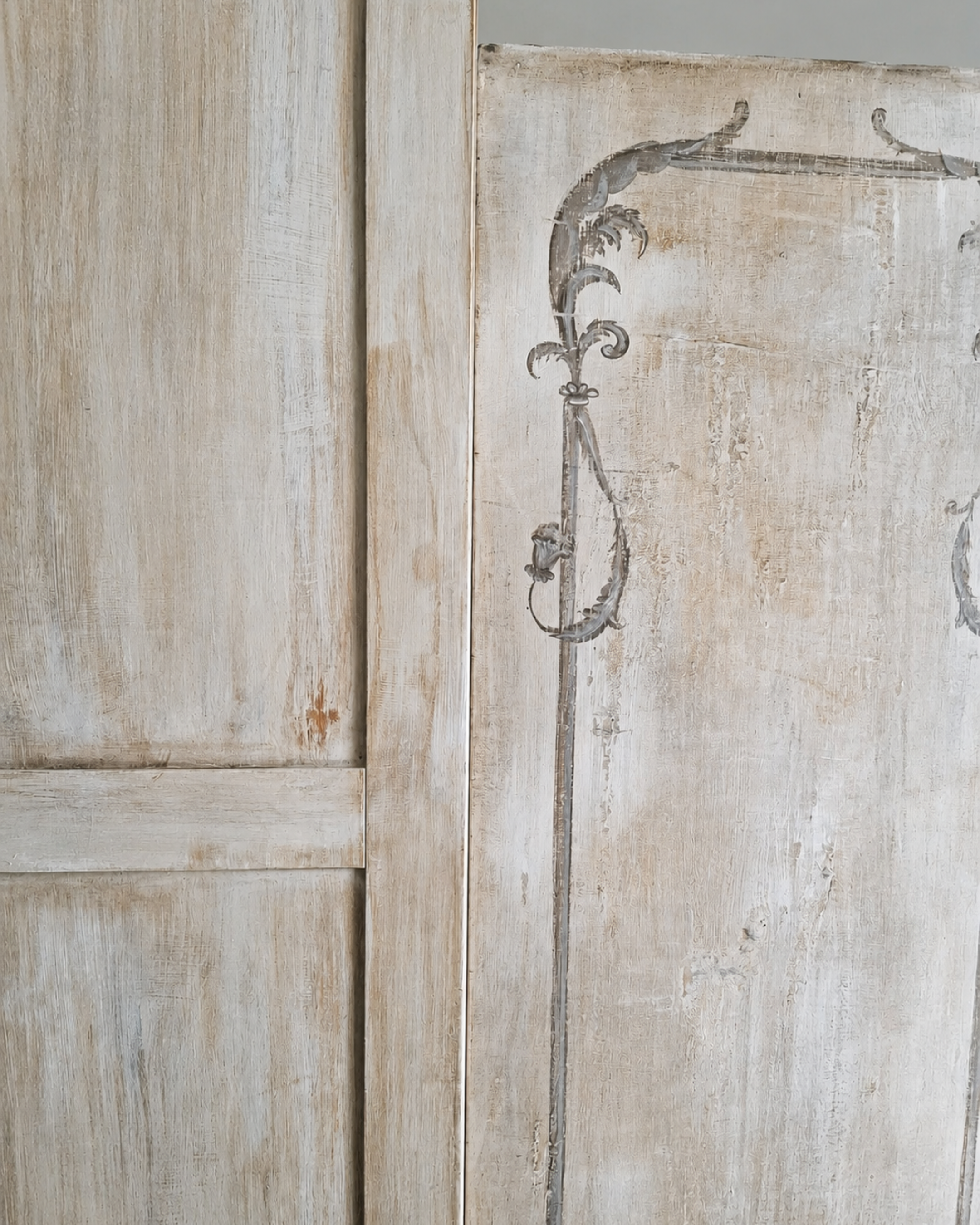 Particolare di una porta in legno chiaro con una decorazione dipinta in stile antico.