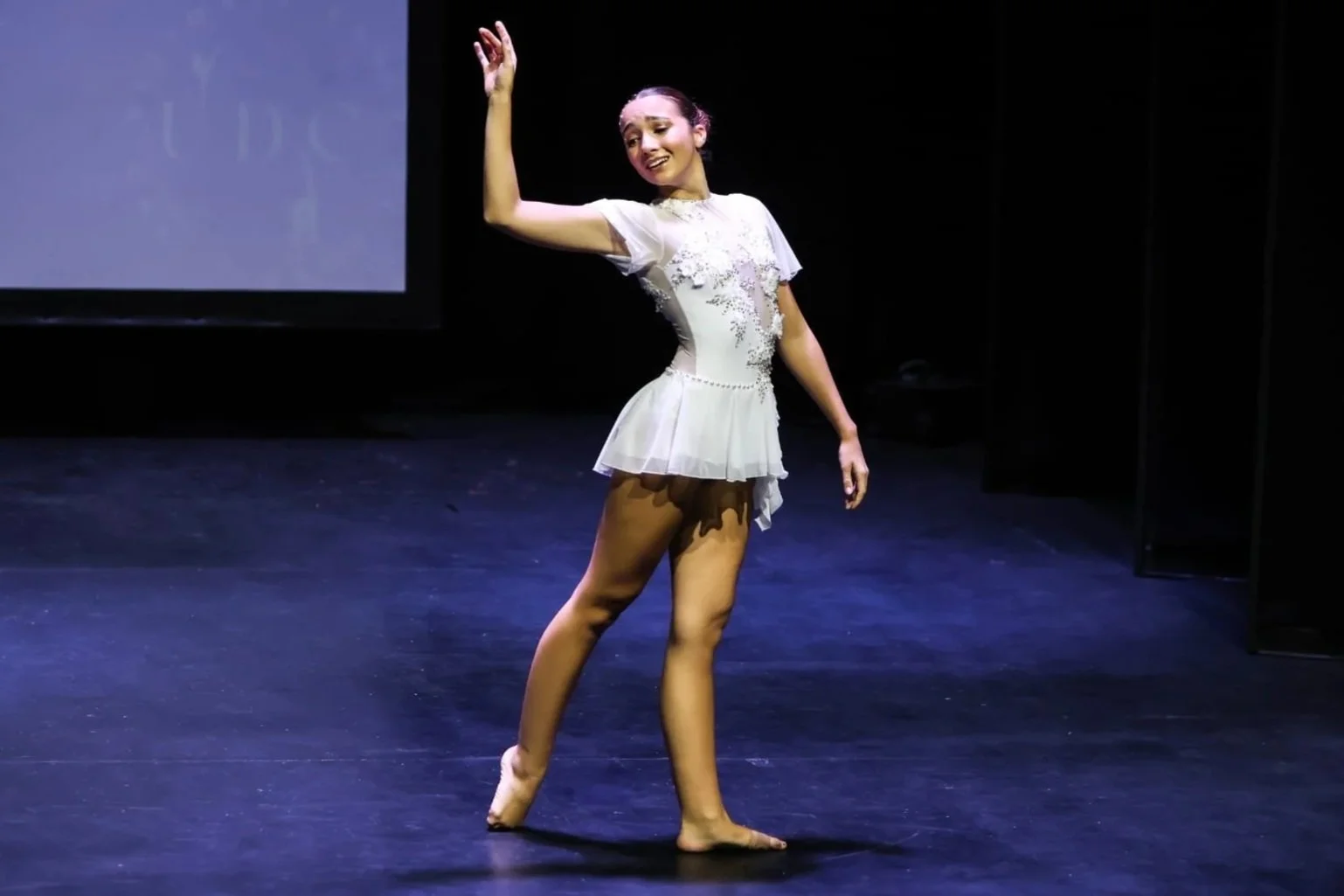 Dancer performing a lyrical solo, wearing a white costume.