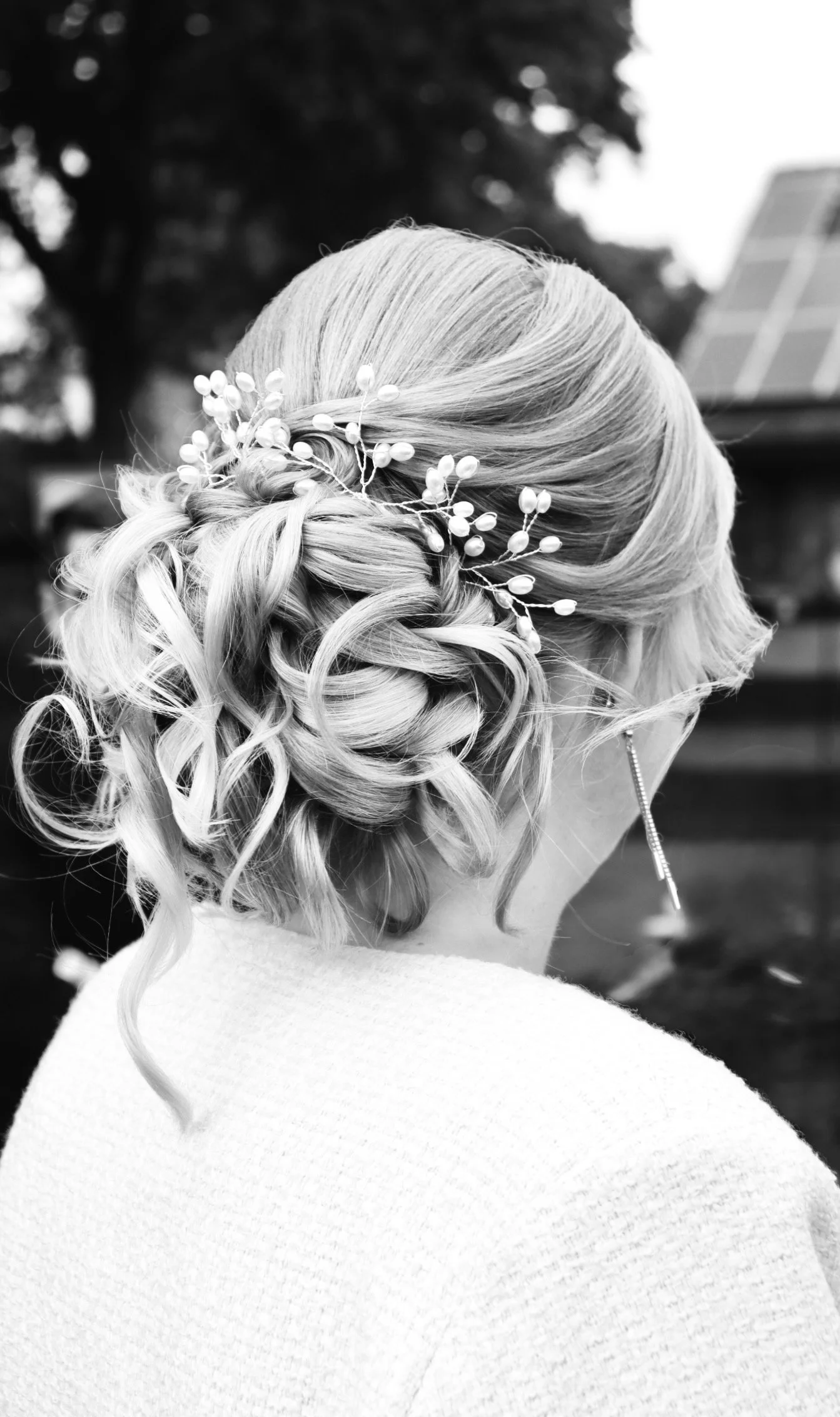 Schwarz-Weiß-Foto einer Braut mit elegantem lockigem Hochsteckfrisur und filigranem Blüten-Haarschmuck am Tag ihrer Hochzeit 