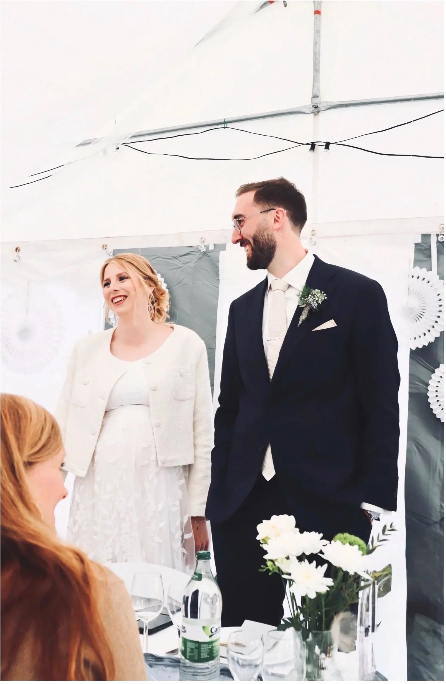 Hochzeitsfotografie Nähe Hannover, Bremen, Nienburg und Region, Lachendes Brautpaar bei einer Hochzeitsfeier mit Blumenstrauß und festlich gedecktem Tisch
