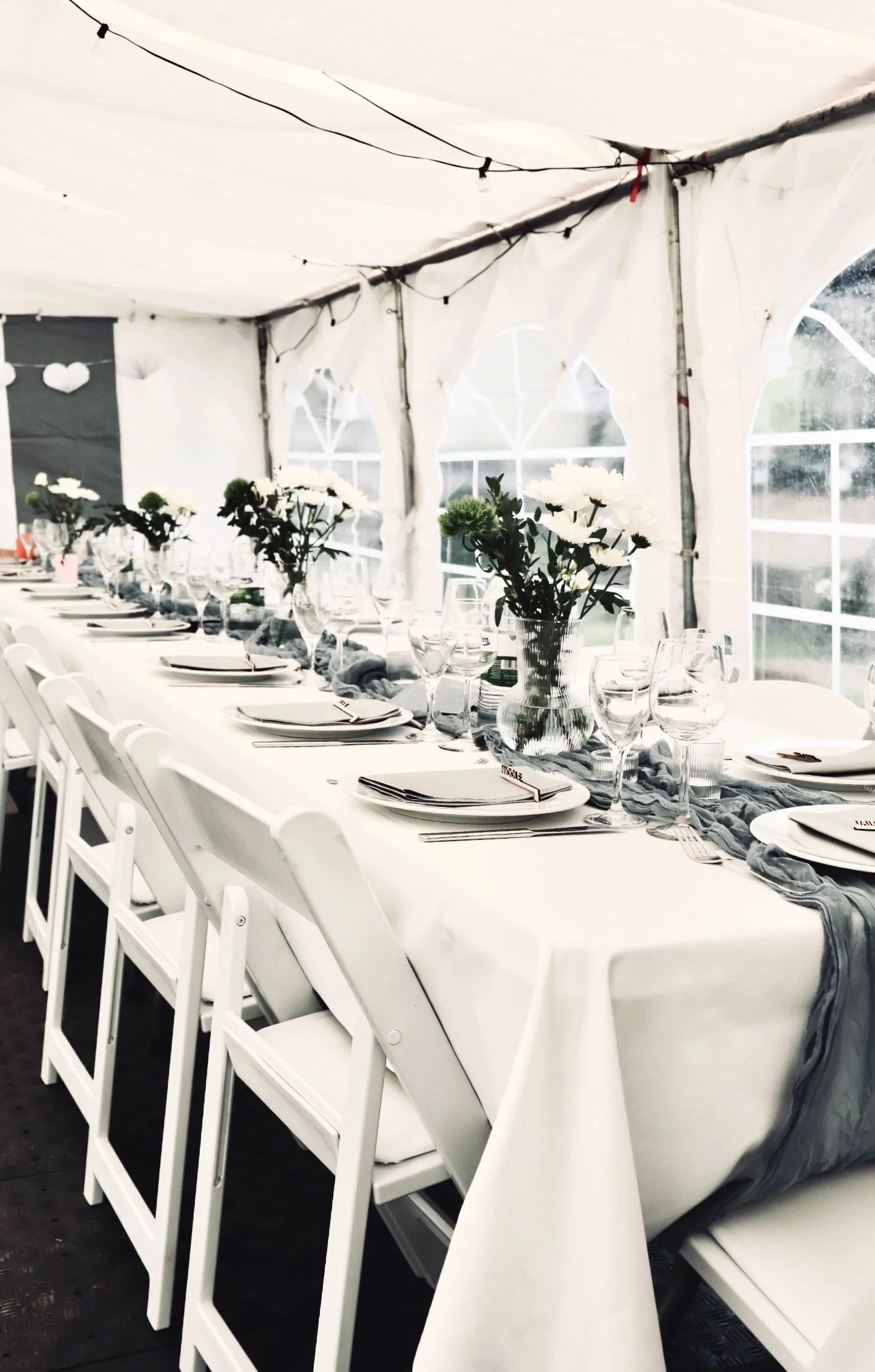 Hochzeitsfotografie Nähe Hannover, Bremen, Nienburg und Region, Festlich gedeckte Hochzeitstafel in einem weißen Festzelt mit Blumenvasen, Glasgeschirr und Lichterketten, Hochzeitsfotografie Nähe Hannover, Bremen, Nienburg und Region
