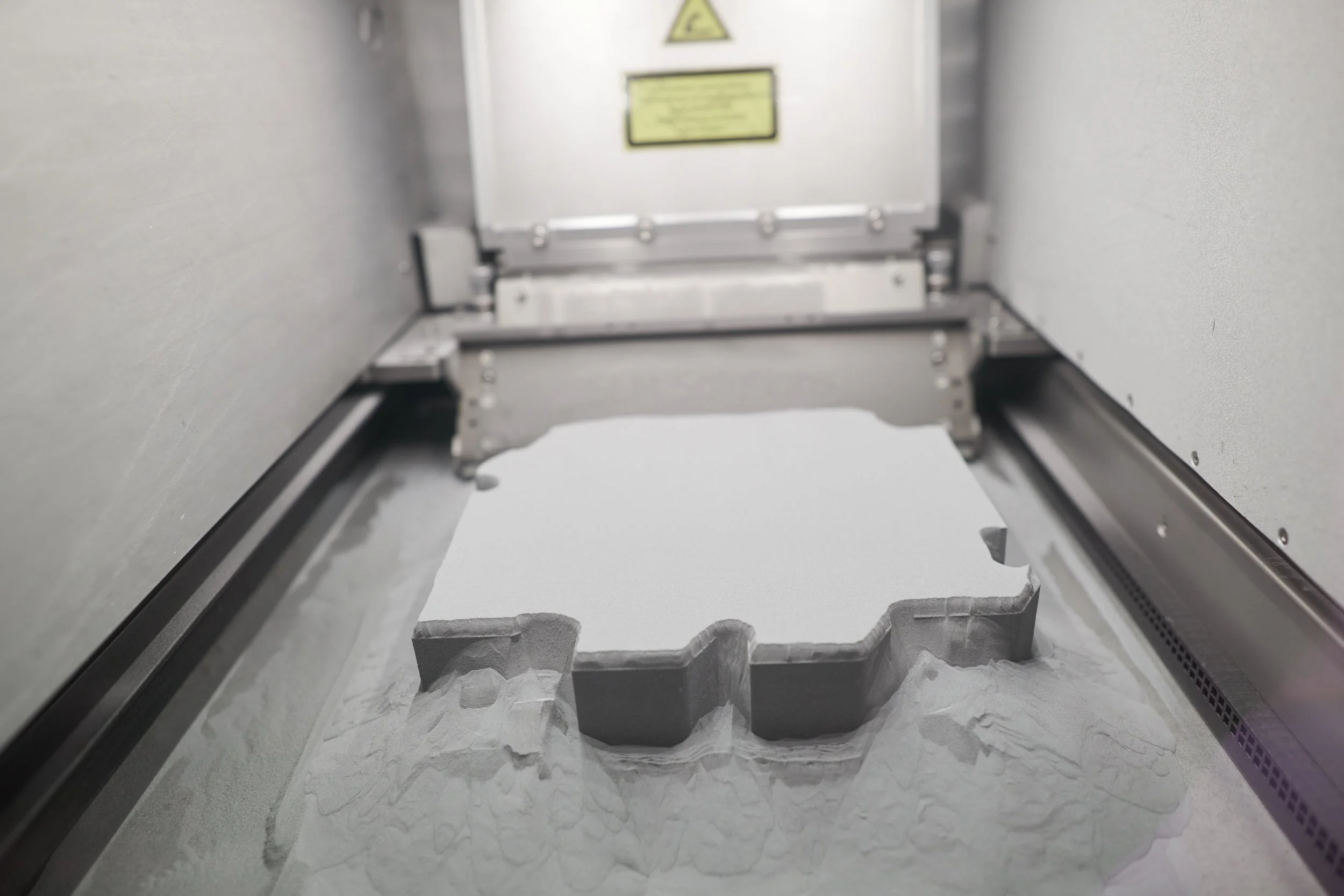 Metallpulverbett mit aufgebautem Bauteil im SLM-Drucker bei Trivion