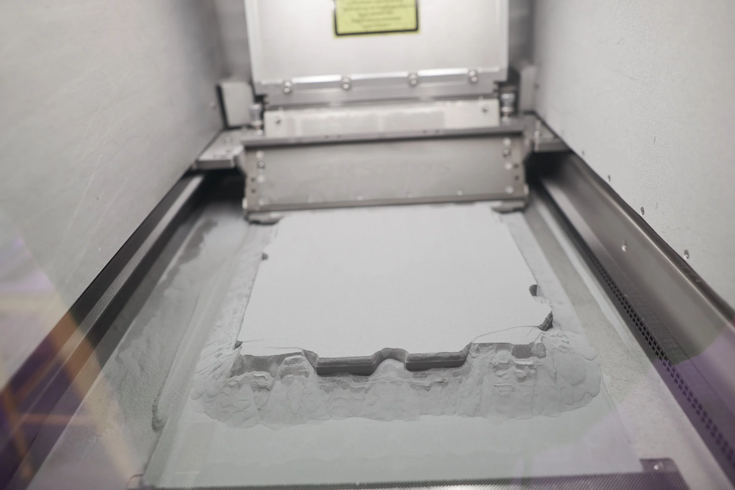 Metallpulverbett mit aufgebautem Bauteil im SLM-Drucker bei Trivion