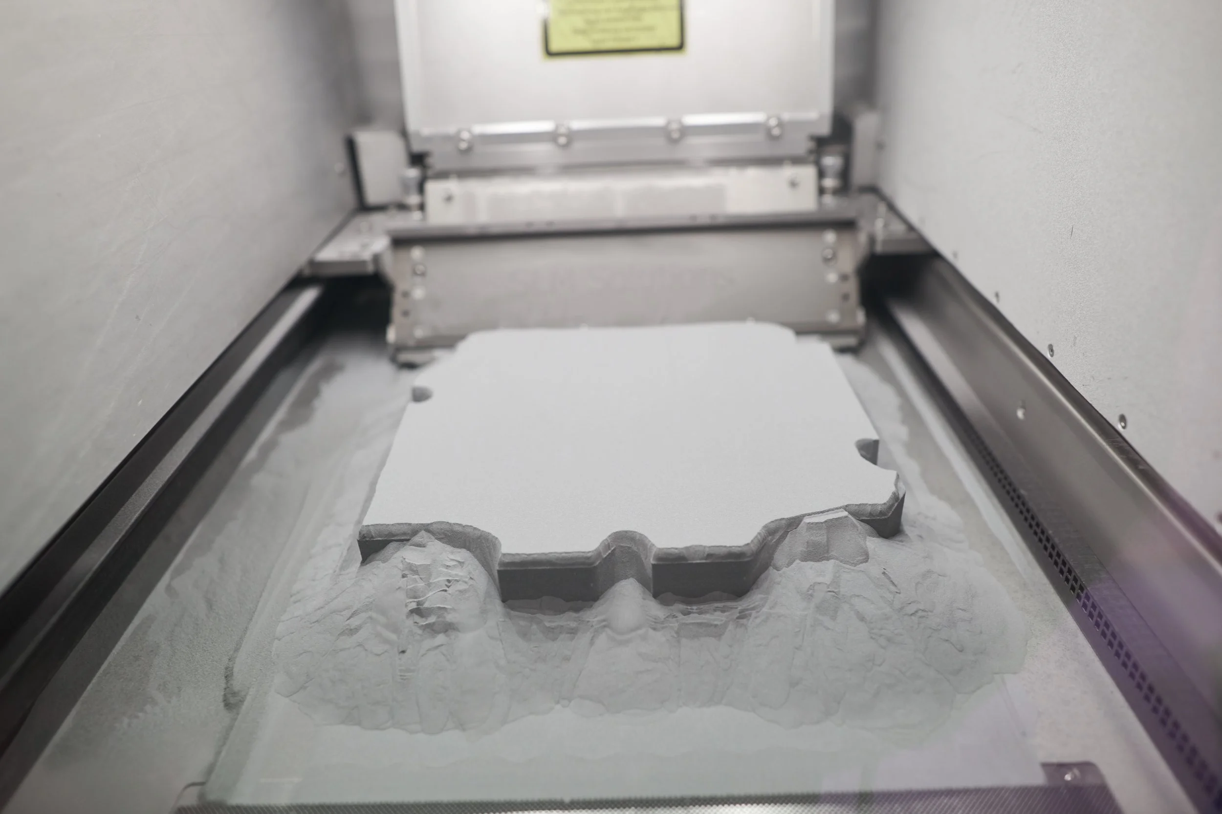 Metallpulverbett mit aufgebautem Bauteil im SLM-Drucker bei Trivion