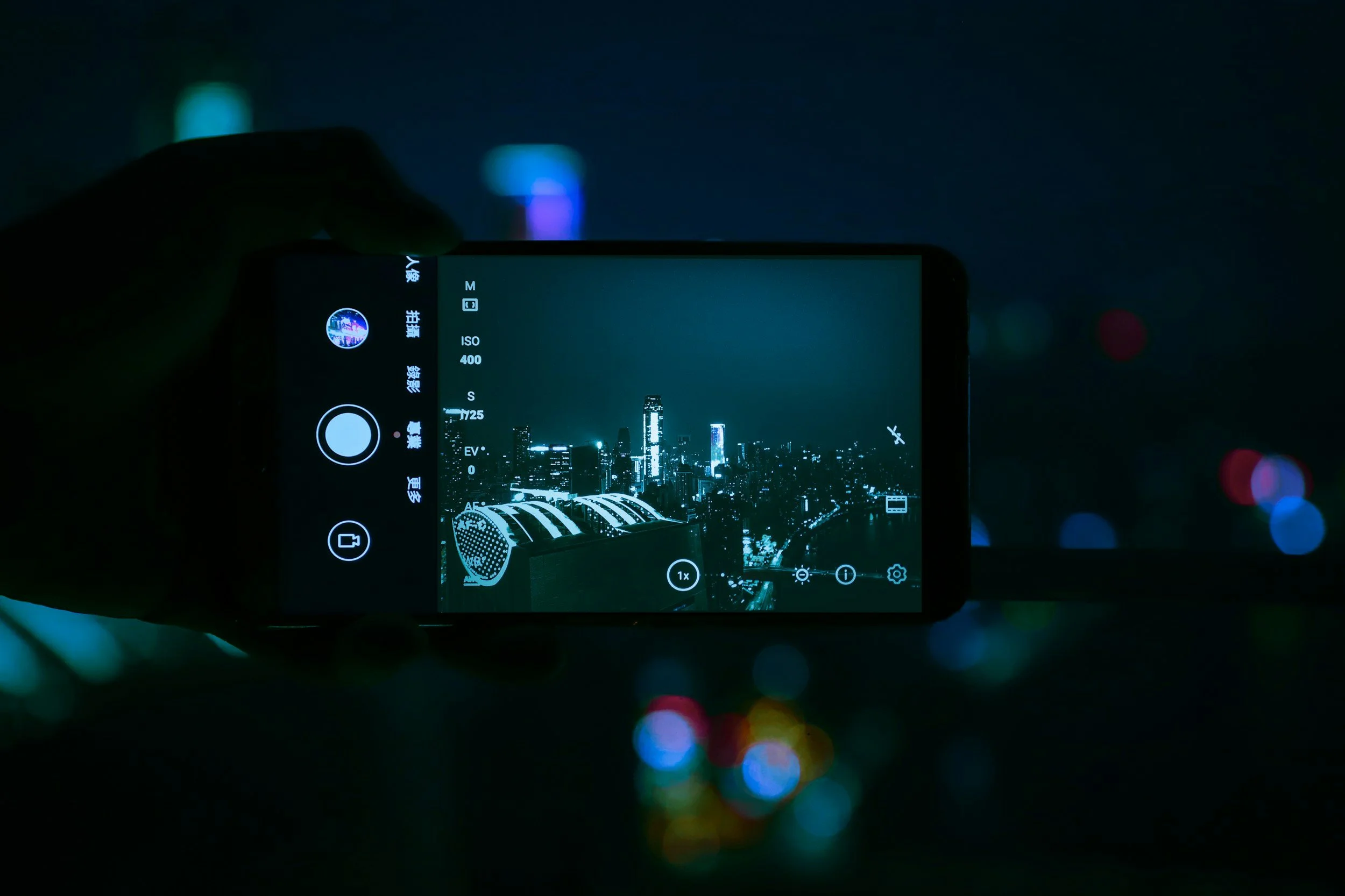 A smartphone capturing a nighttime cityscape with illuminated skyscrapers.