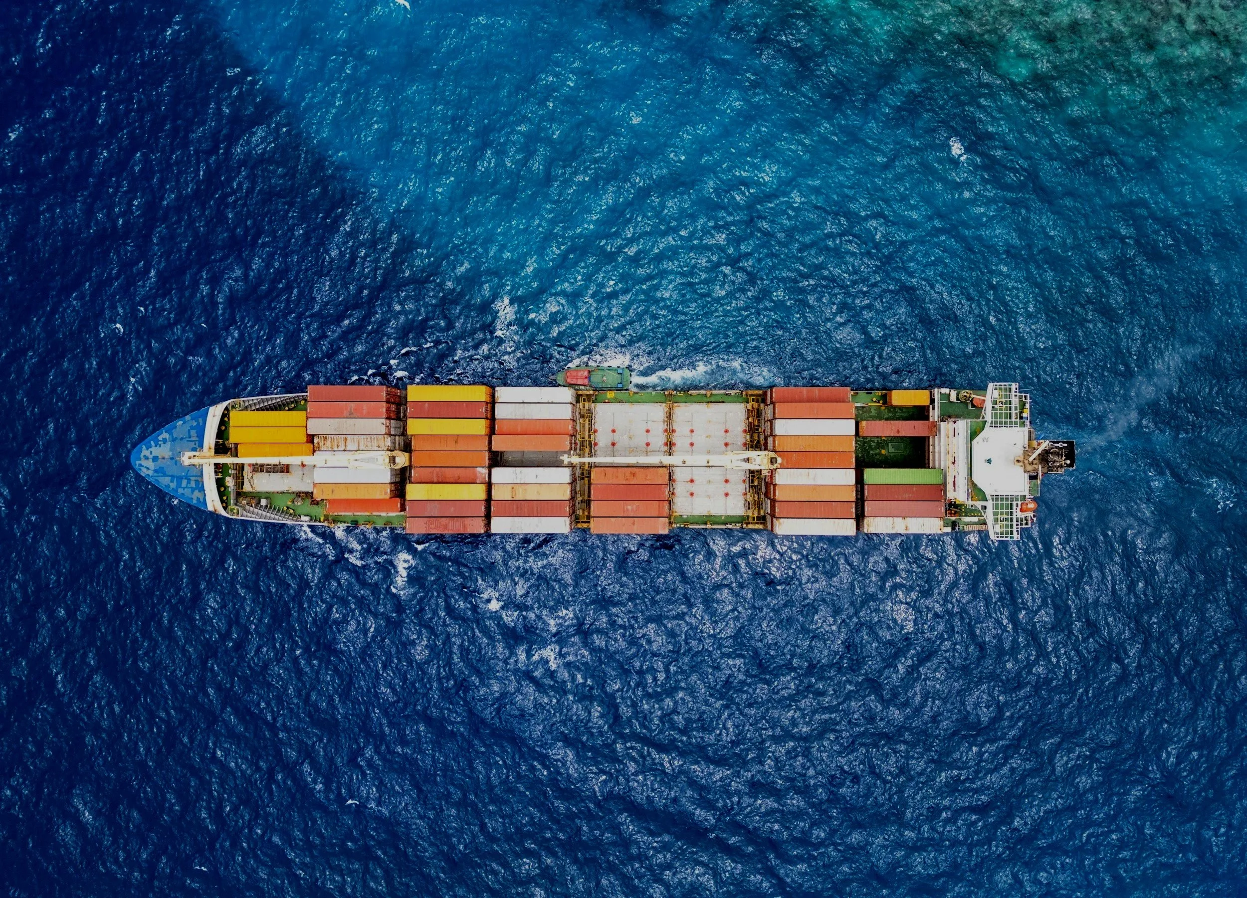 An aerial view of a large cargo ship with containers, sailing on the ocean.