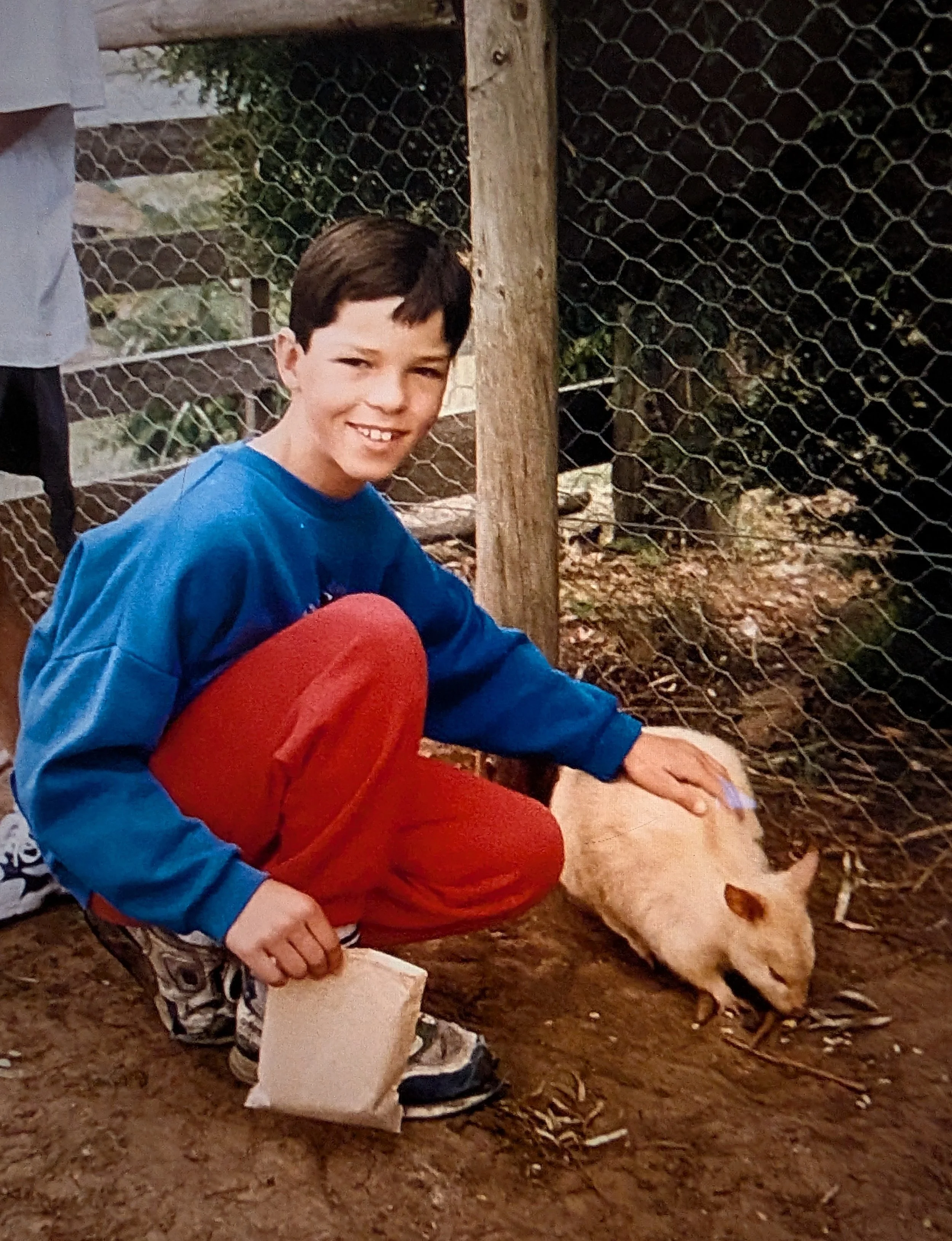 Greg Irons as a child visiting Bonorong and patting a golden Tasmanian pademelon