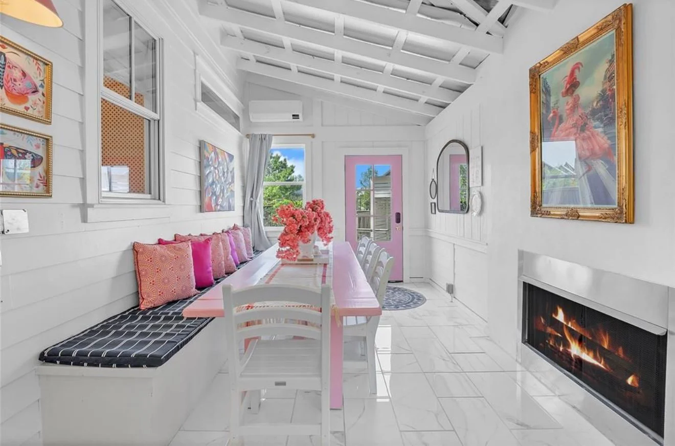 Pink Firefly Cottage converted enclosed porch with fireplace and large table for family to enjoy together in Carlton Landing Oklahoma