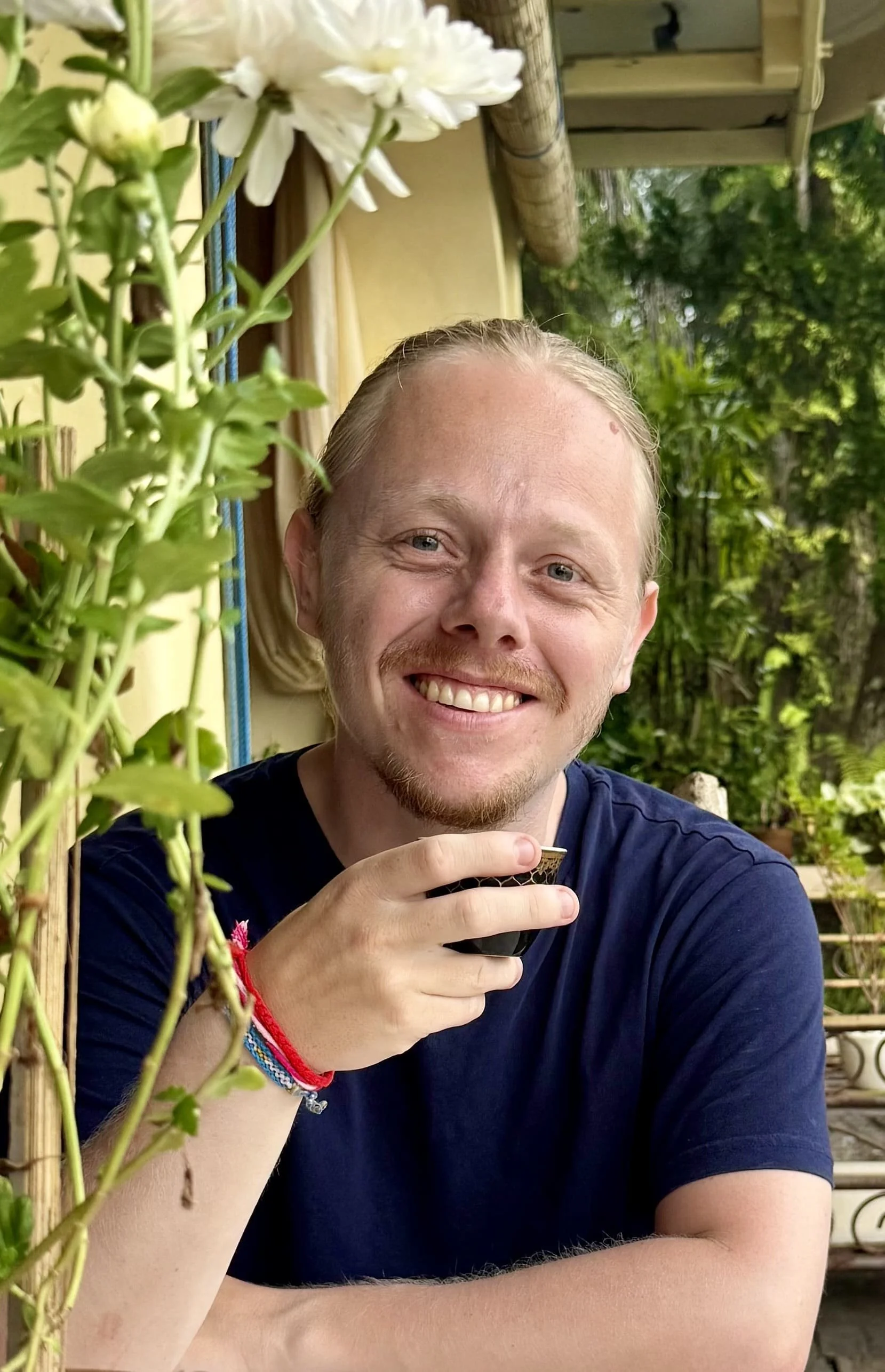 Coach Job de Bruijn glimlachend in een groene tuin wat symbool staat voor zijn innerlijke reis en vrijheid