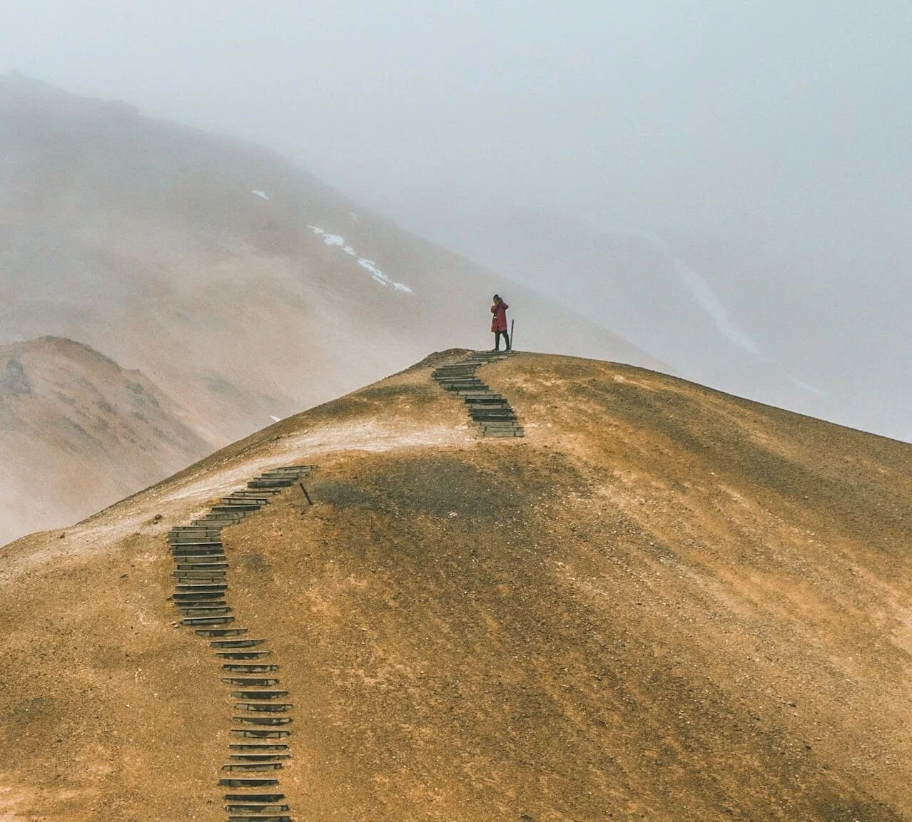 Persoon op een wandelpad naar bergtop wat staat voor een langdurig transformatietraject om je authentieke zelf te belichamen