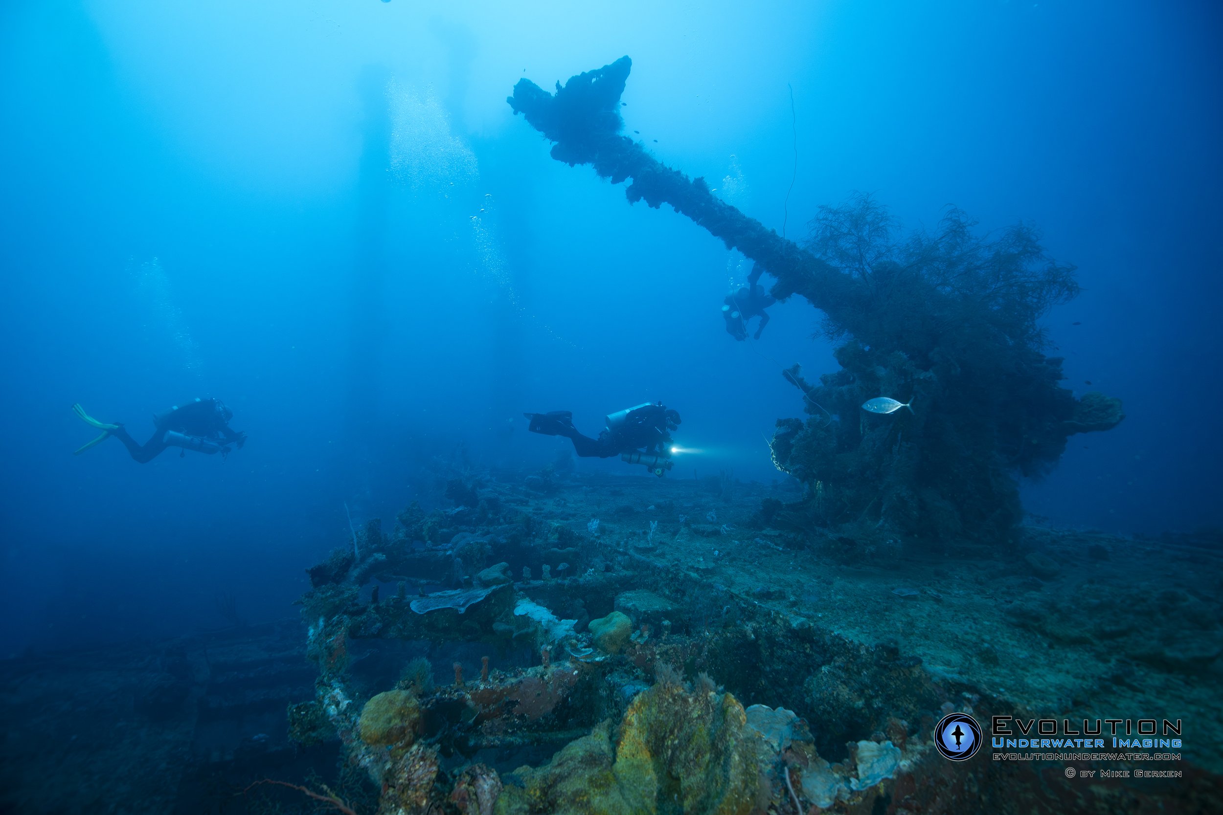 Underwater scene with scuba divers exploring the shipwreck Aikoku Maru in Truk Lagoon.