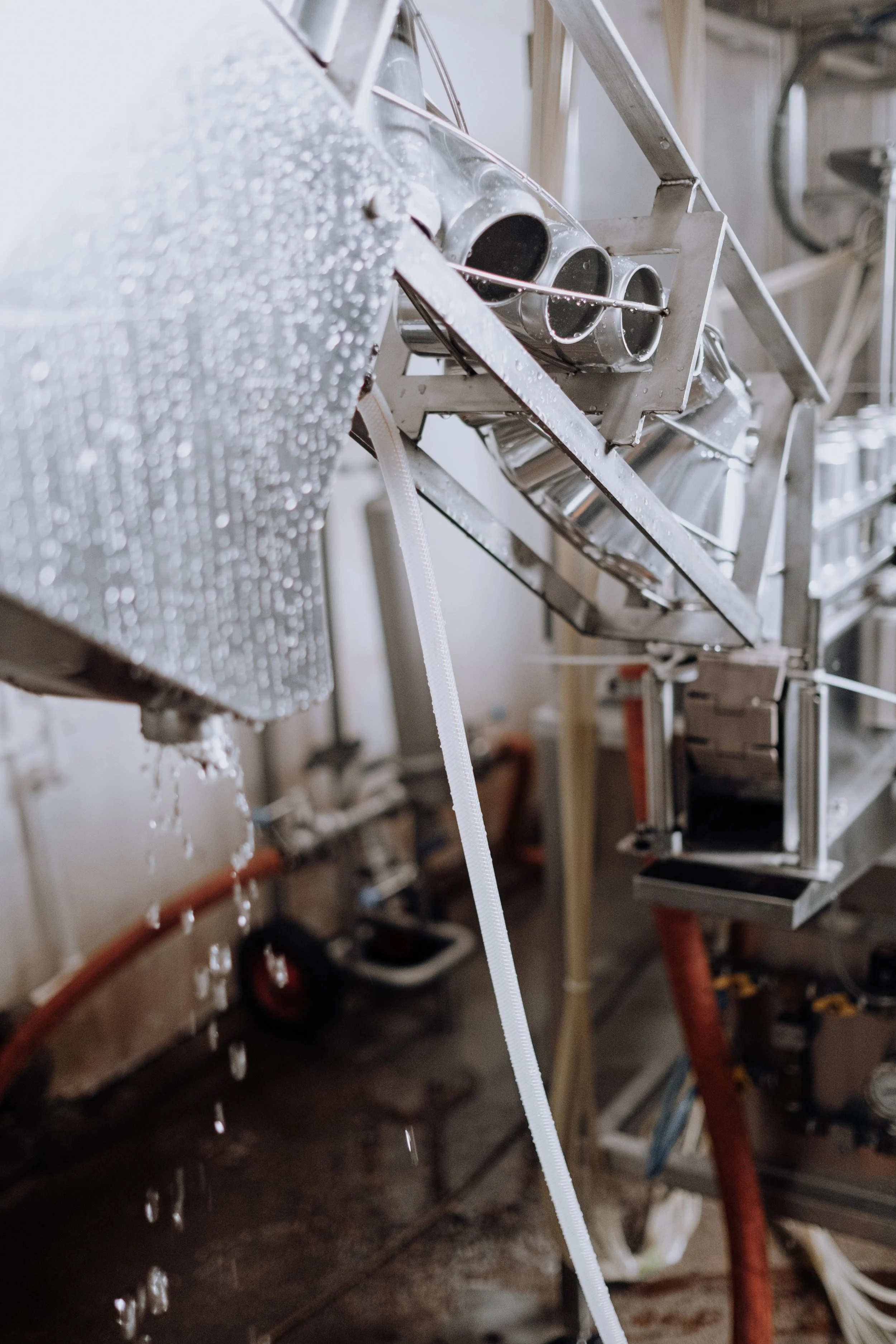 Close-up of a metal structure with pipes, water droplets, and a white rope or cable, likely part of an industrial or mechanical setting.