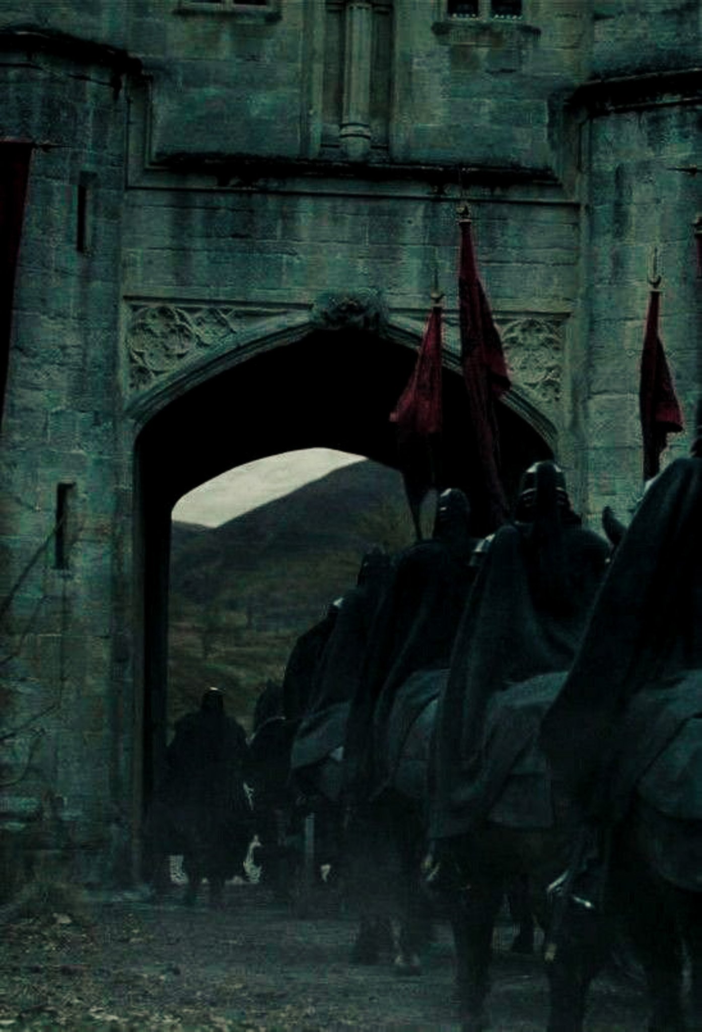 Horses pulling a carriage through a stone archway in a medieval-style town.