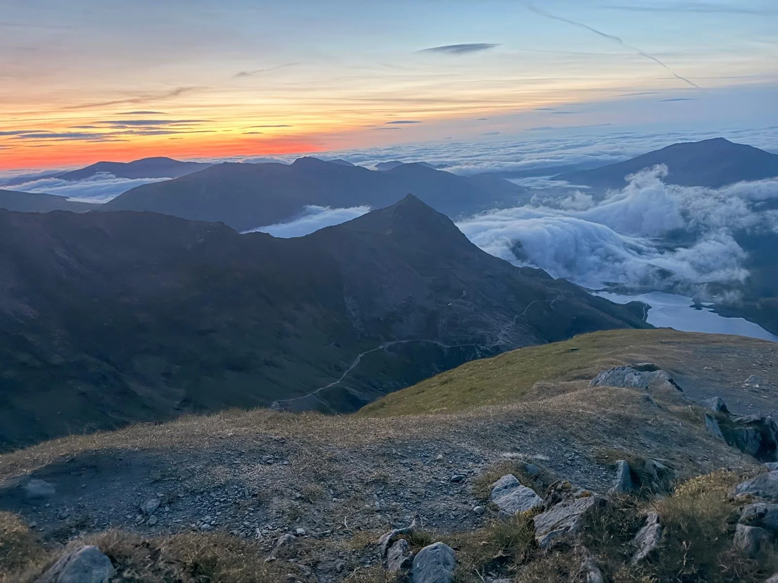 Scenic view of a mountain range during sunset with clouds and a colorful sky.