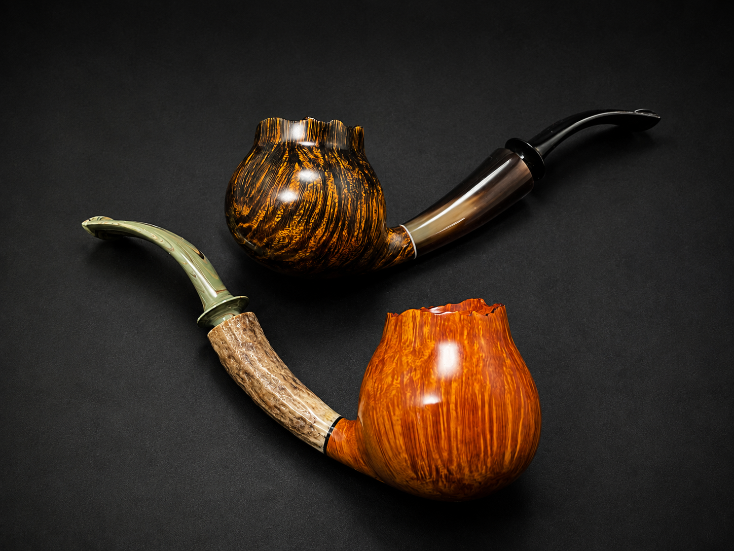 Two decorated smoking pipes with wooden and marble-like finishes on a black surface.