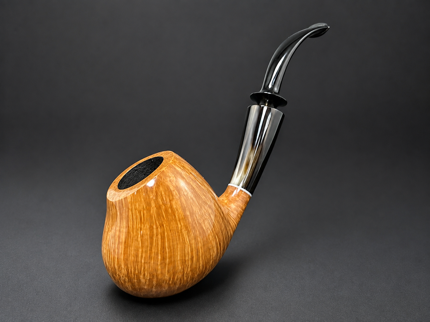 A tobacco pipe with a wooden bowl and a curved black stem against a dark gray background.