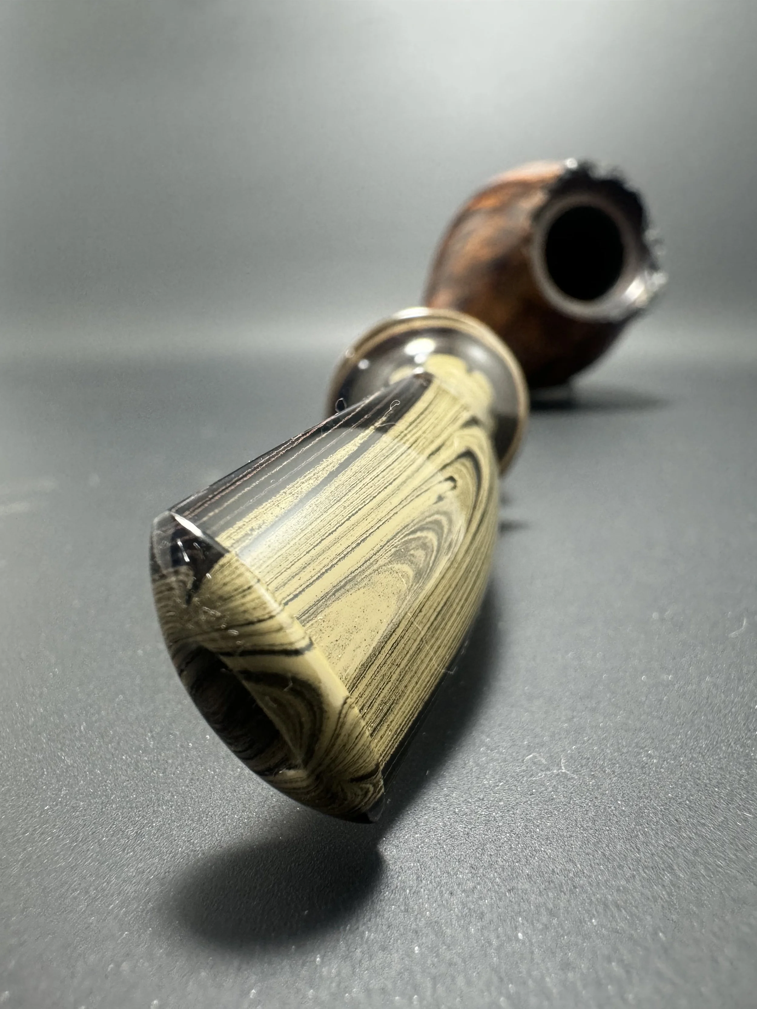 Close-up of a fountain pen resting on a dark surface, with the nib area prominently in focus and the back part of the pen slightly blurred.