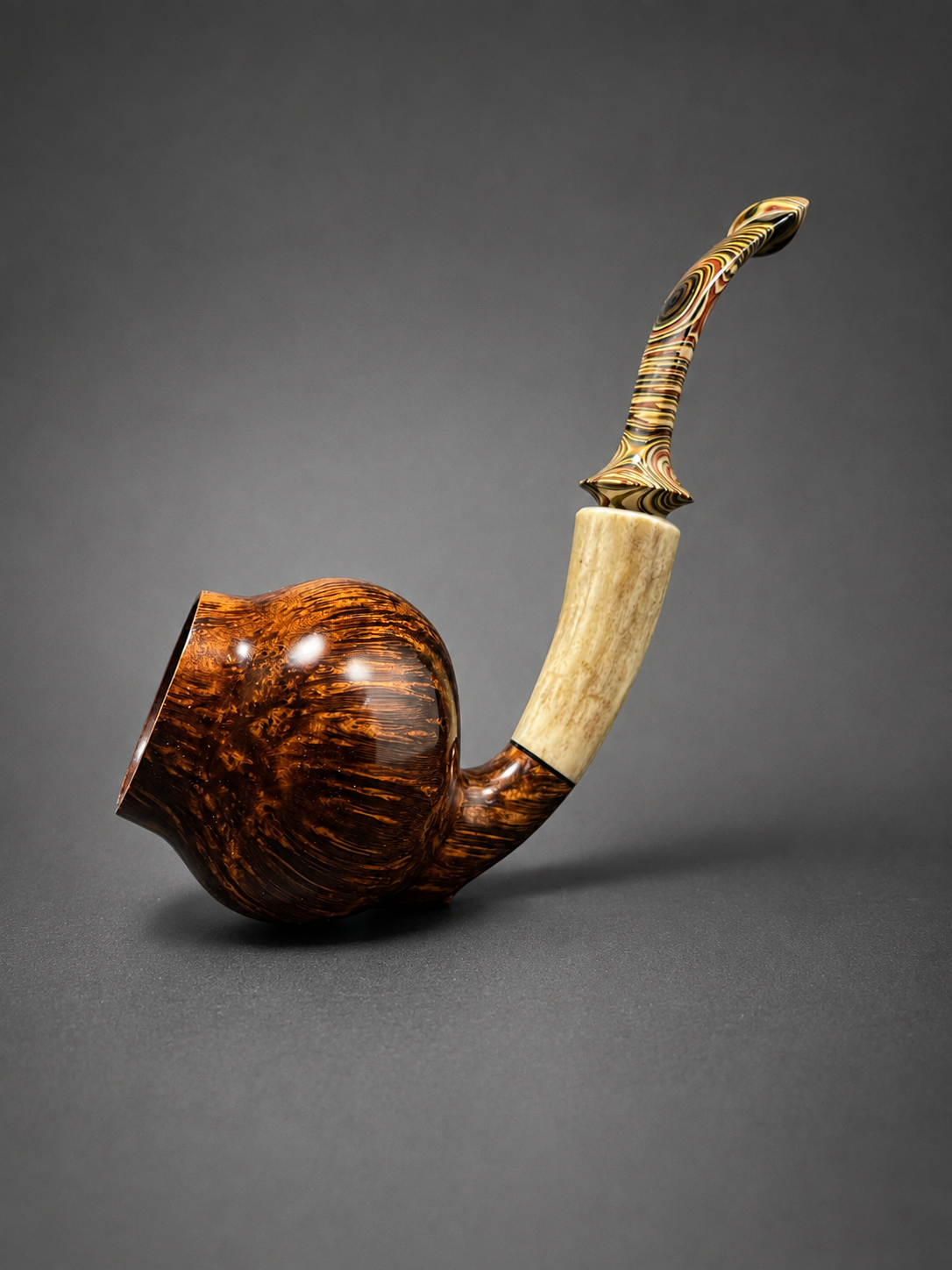 A decorative smoking pipe made of wood and bone, with a swirling patterned mouthpiece, set against a gray background.