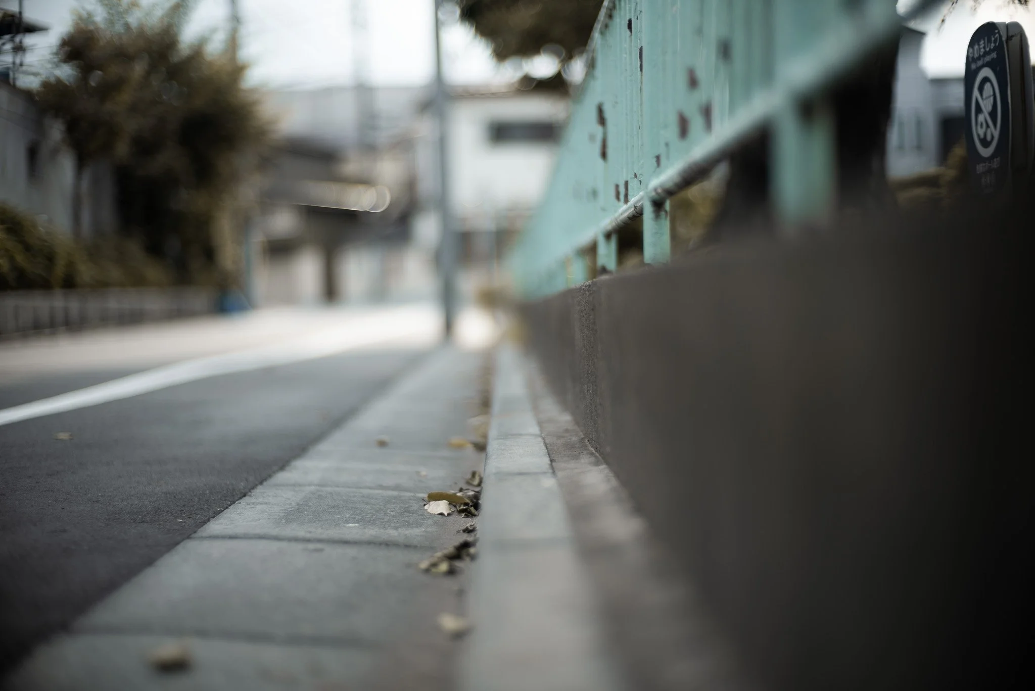 低い角度から見た街の歩道と縁石、落ち葉が散らばっている
