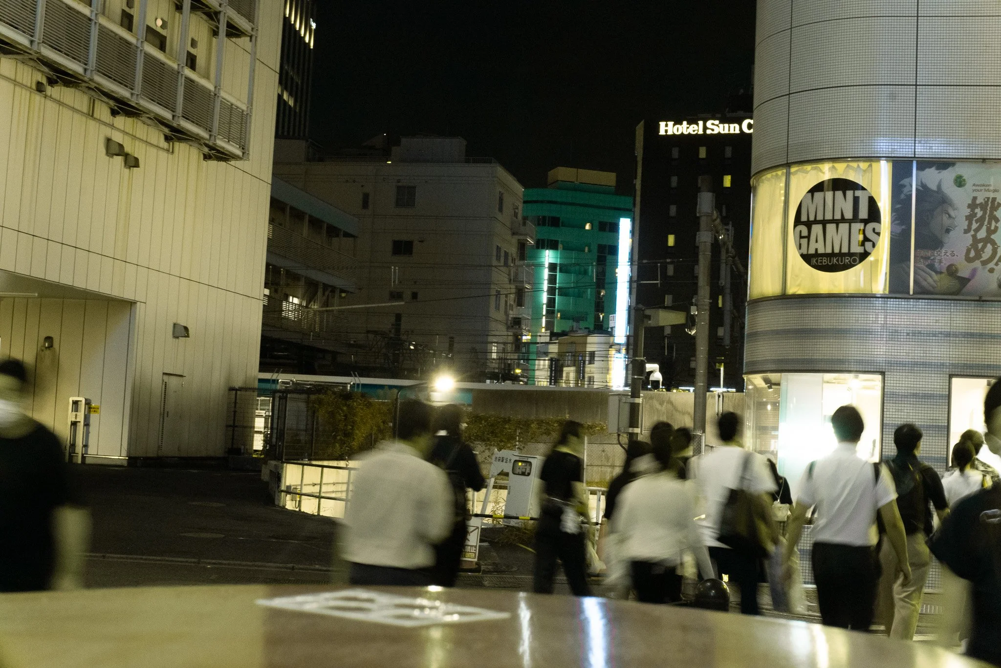 夜の繁華街で人々が通りを歩いている。