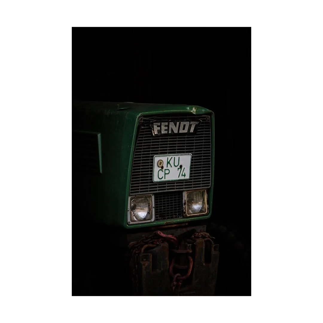 Ein grünes alter Fendt Traktor vor einem schwarzen Hintergrund, mit deutschem Kennzeichen 'KU CP 74'.