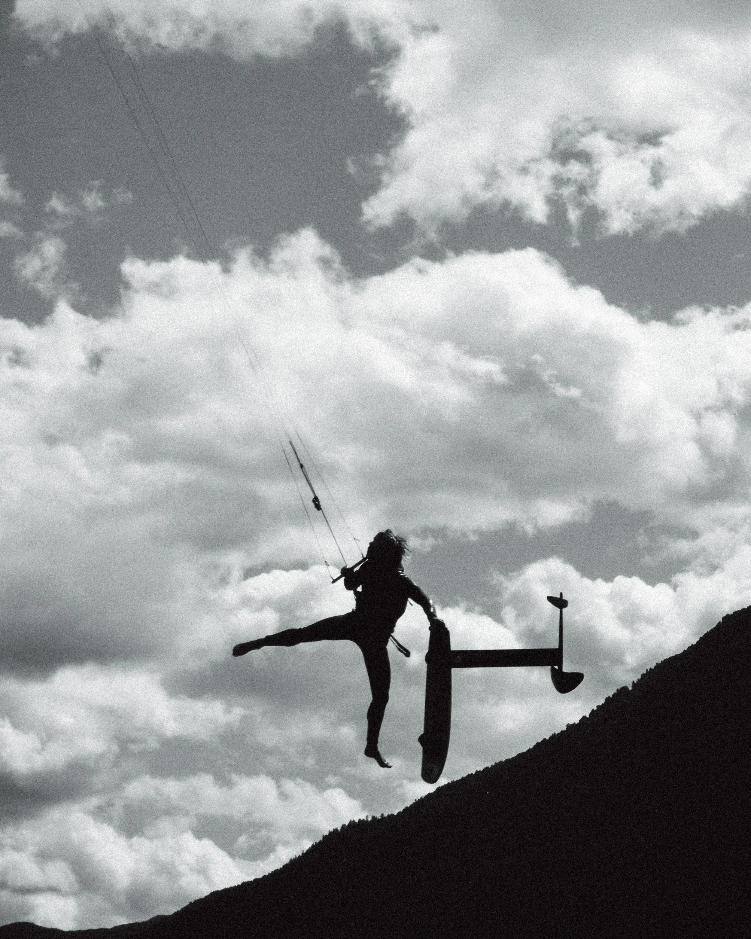 Schwarz-Weiß-Bild von einer Person, die kitet, mit Wolken im Himmel im Hintergrund.