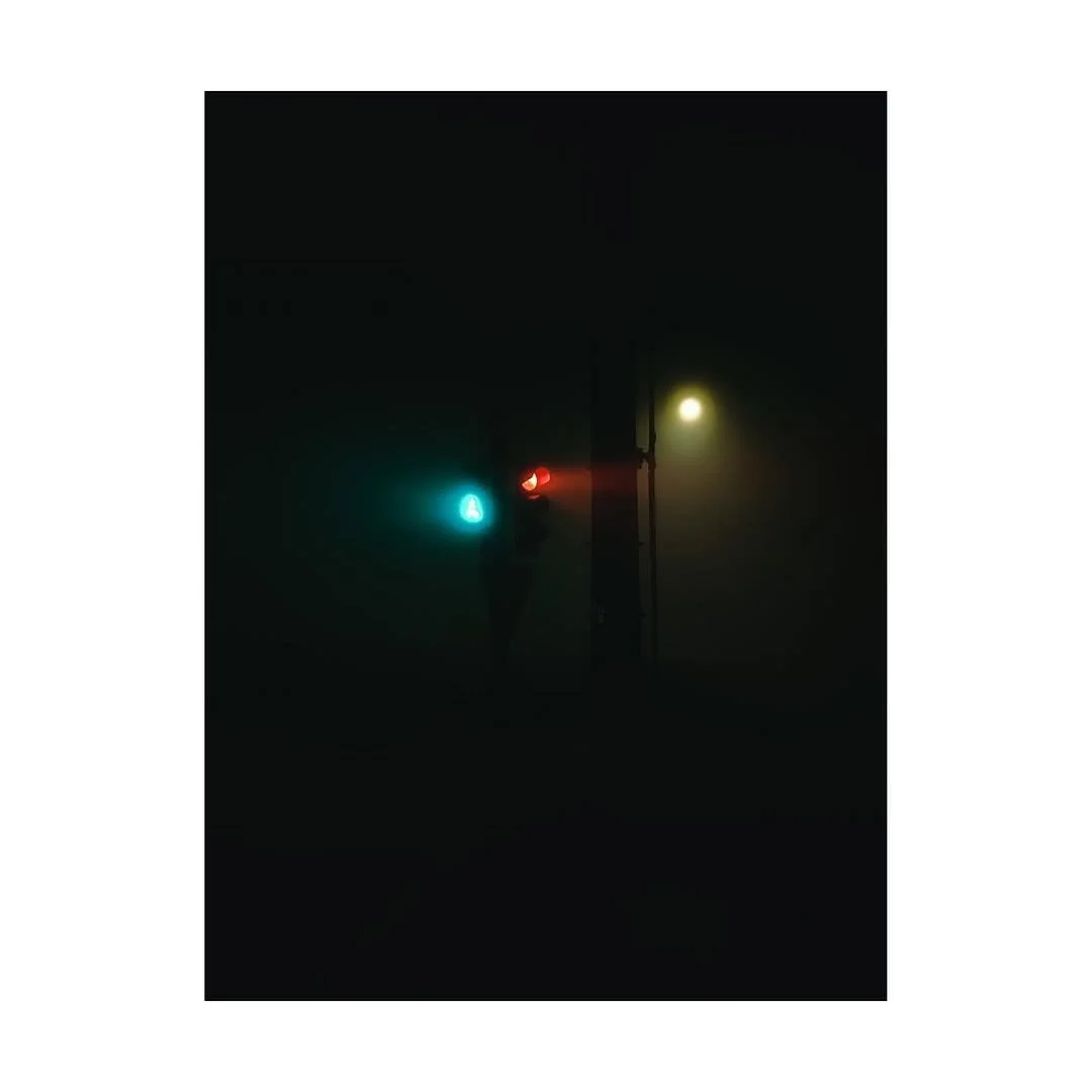 Verkehrsampel in dunkler Nacht, leuchtend in Blau, Rot und Gelb.
