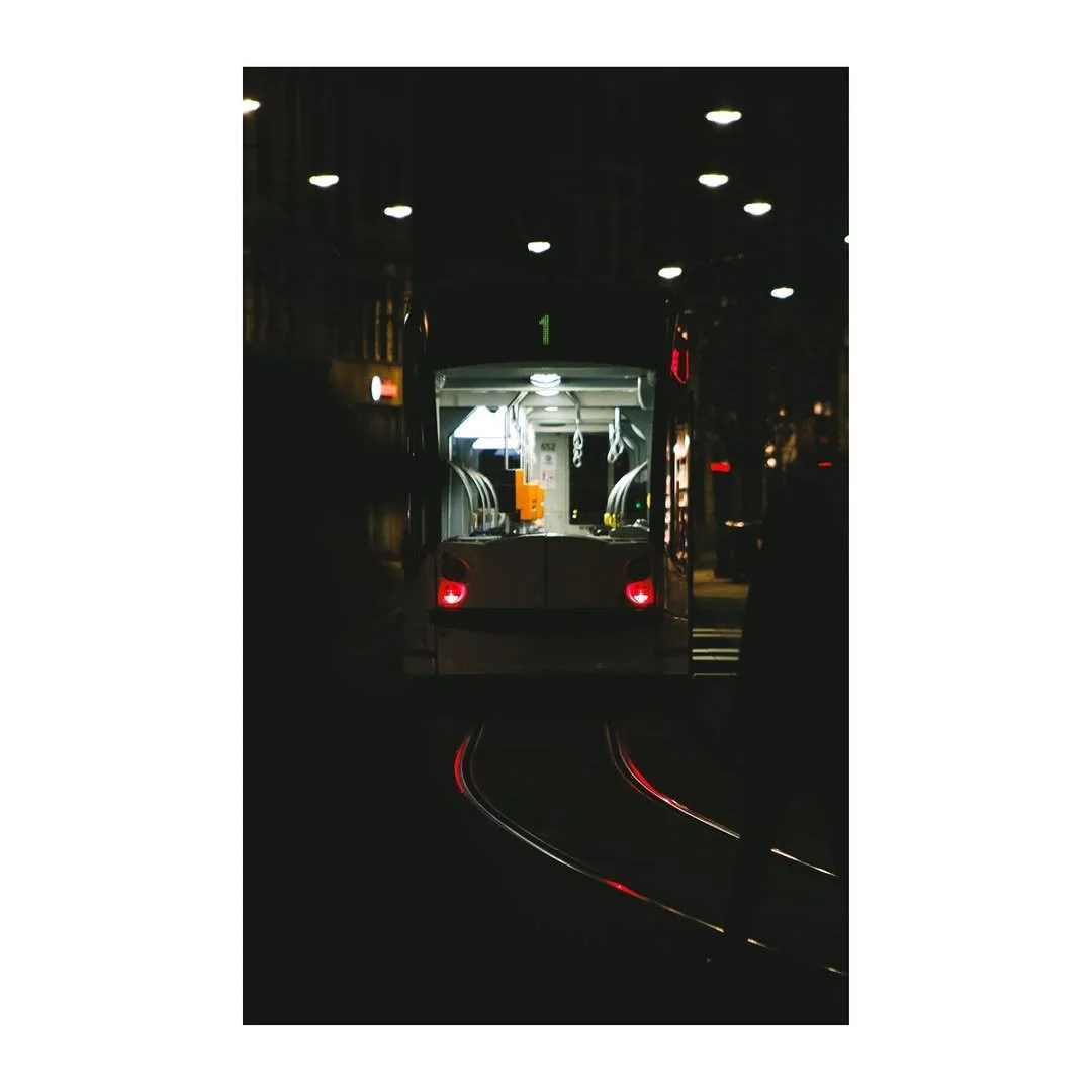 Straßenbahn in der Nacht mit beleuchteter Innenbeleuchtung und reflektierenden Schienen.