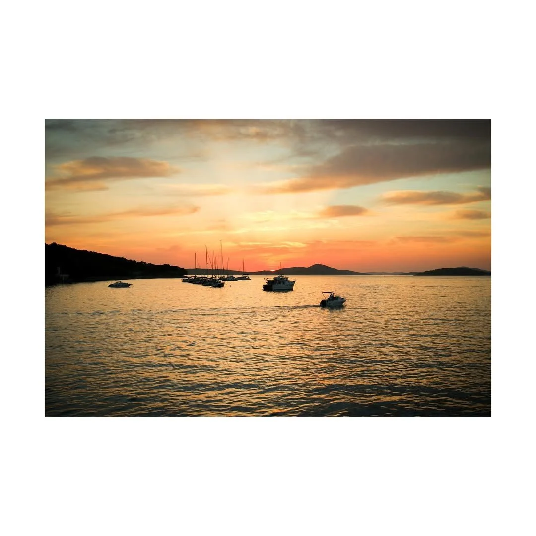 Sonnenuntergang über einem See mit mehreren Booten im Wasser.