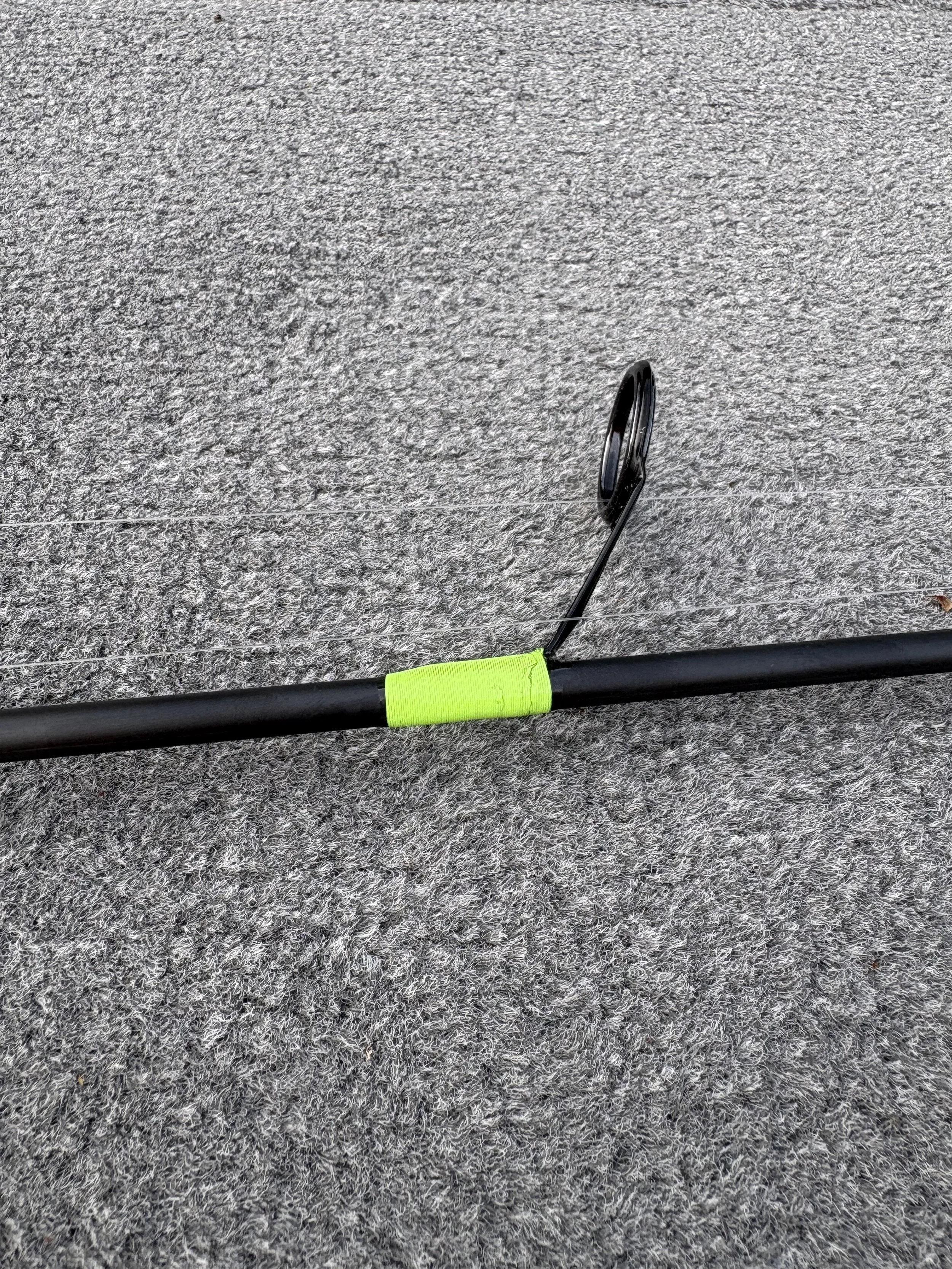 ultra light rod with a green wrapped guide resting on a textured gray carpet.