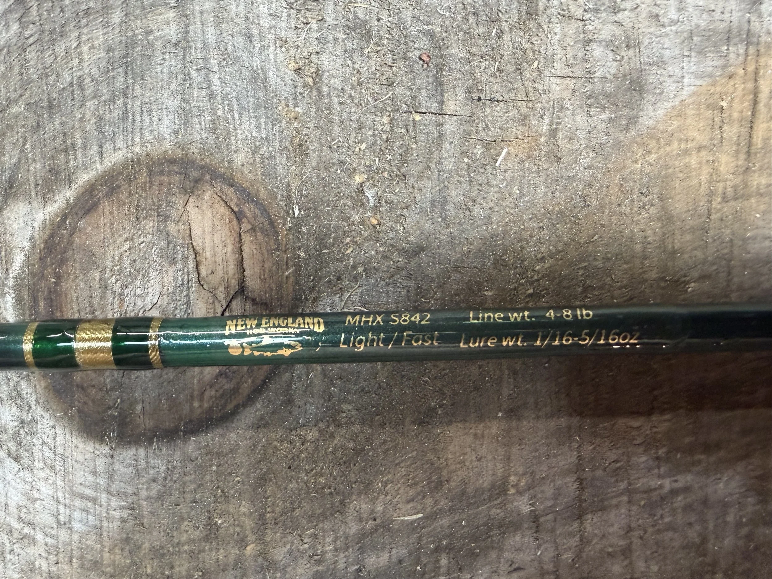 A close-up of a fishing rod lying on a rough concrete surface.