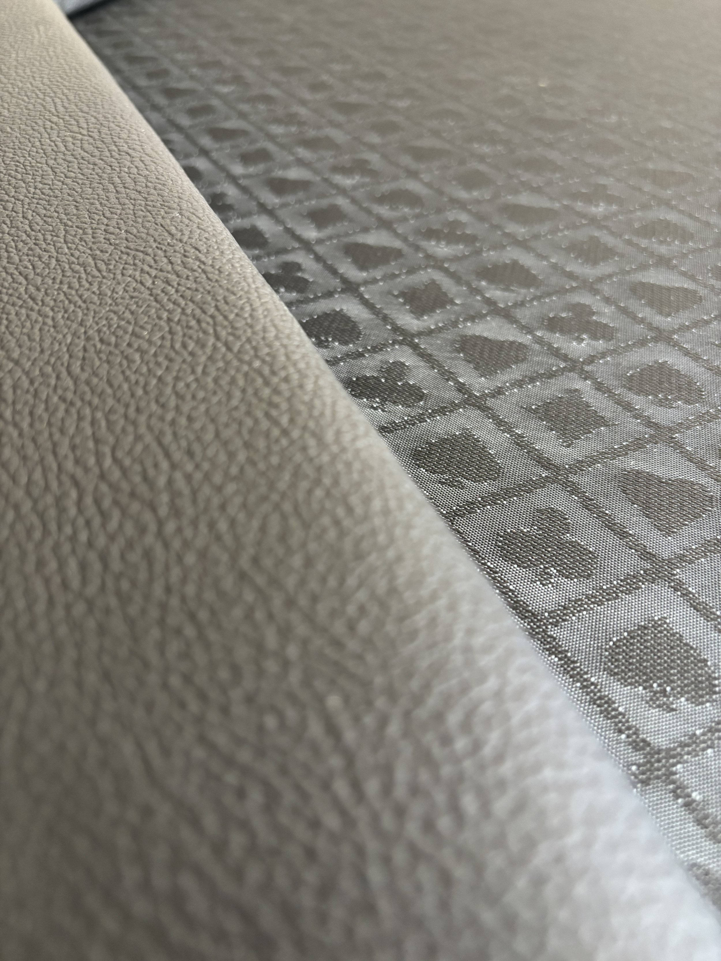 Nahaufnahme von einem beige-farbenen Stoff und einer silbernen, transparenten Folie mit einem Muster aus Quadraten und Kreisen.