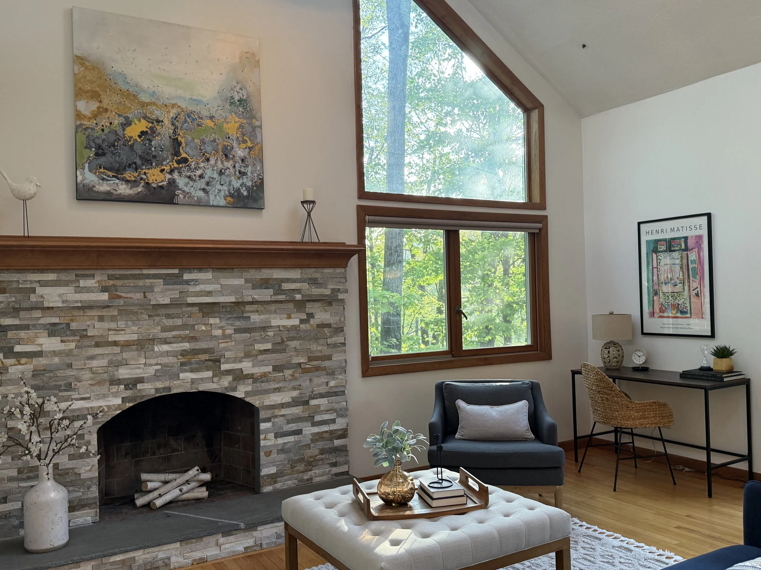 Professionally staged living room with stone fireplace and large triangular window in a Westhampton, MA home.