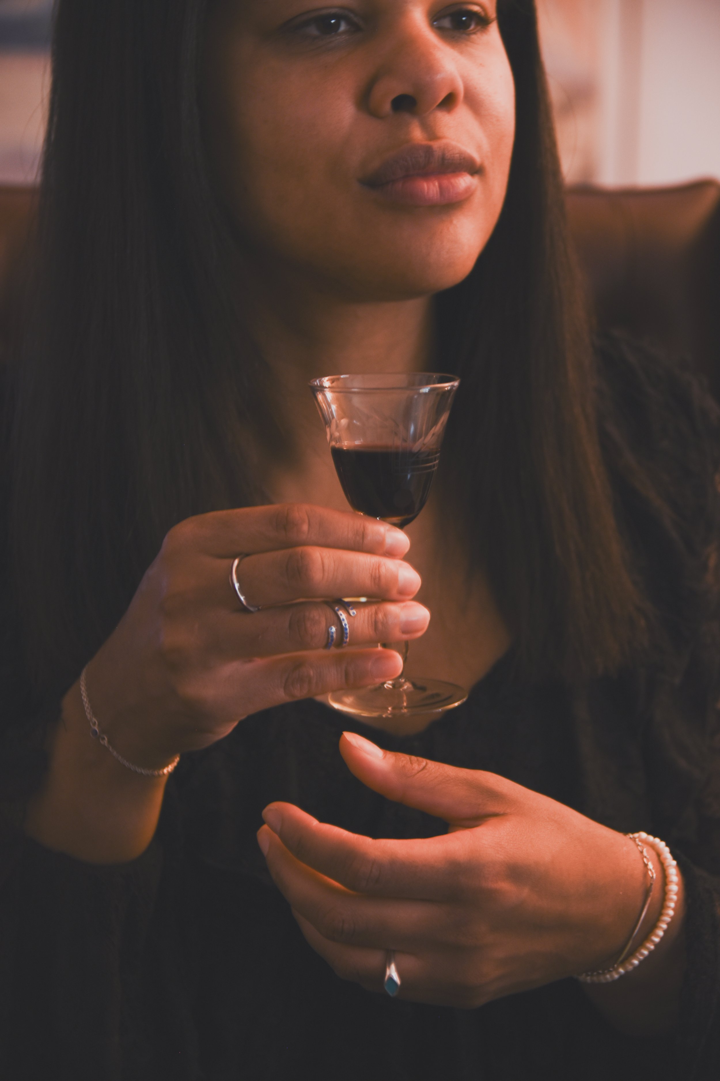A woman holding a glass of red wine in a dimly lit setting.