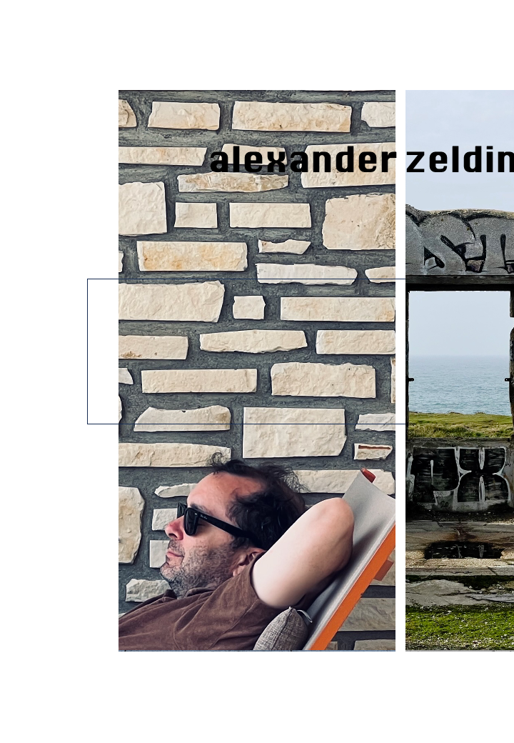 Alexander Zeldin with dark hair, wearing sunglasses and a brown shirt, relaxing with his hands behind his head against a stone brick wall.